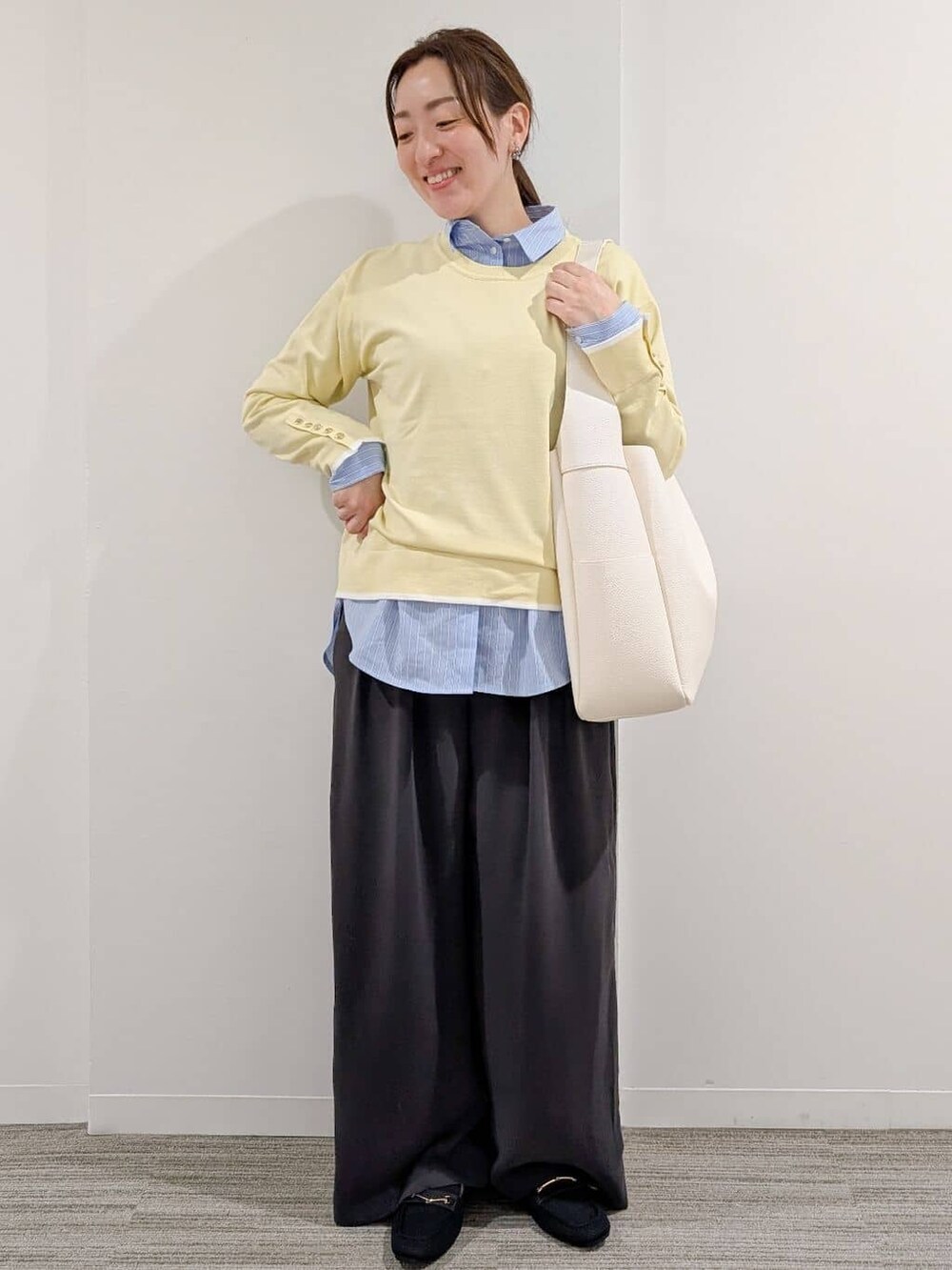 イエロー系のニット/セーター、ブルー系のシャツ/ブラウス、グレー系のその他パンツを着用したレディースの冬コーディネートの3枚目の写真