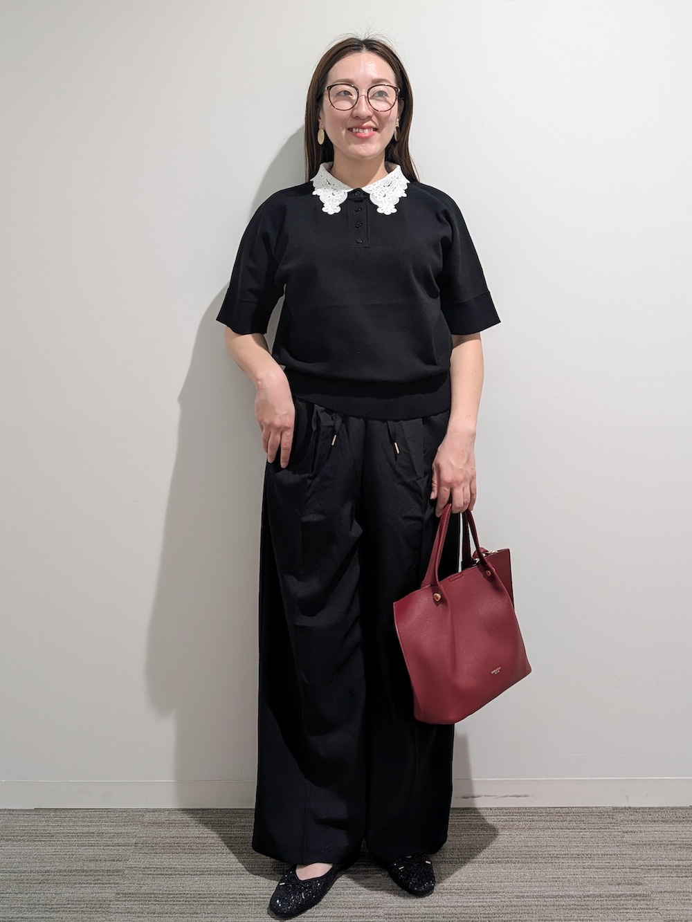 ブラック系のニット/セーター、ブラック系のその他パンツ、レッド系のショルダーバッグを着用したレディースの秋コーディネートの2枚目の写真