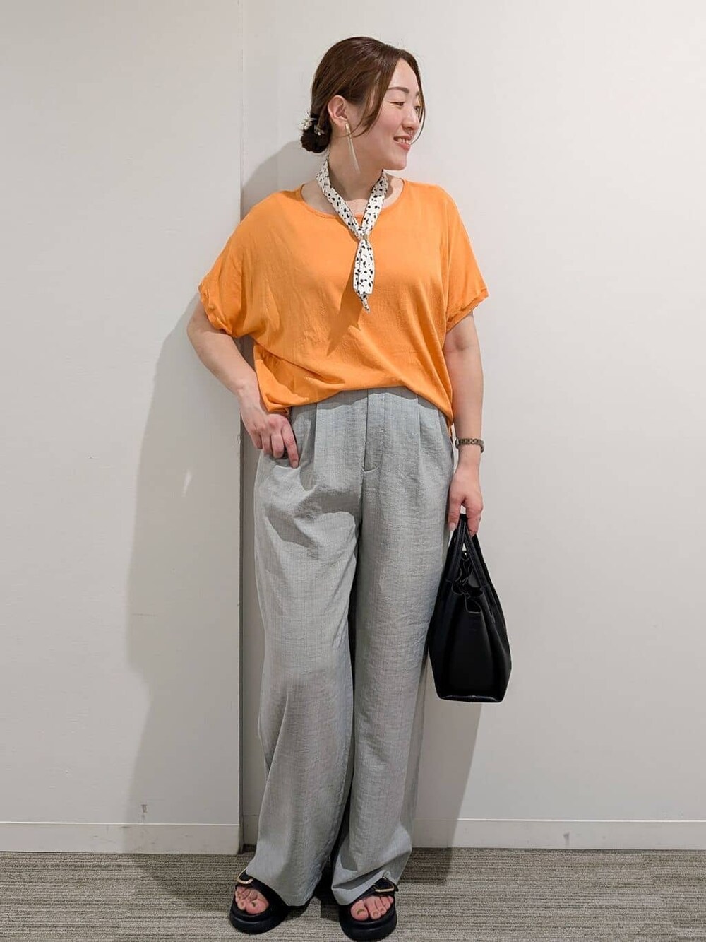 オレンジ系のニット/セーター、グレー系のその他パンツ、ブラック系のサンダルを着用したレディースの夏コーディネートの6枚目の写真