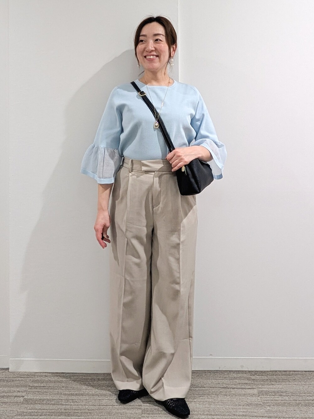 ブルー系のニット/セーター、ベージュ系のその他パンツ、ブラック系のショルダーバッグを着用したレディースの春コーディネートの2枚目の写真