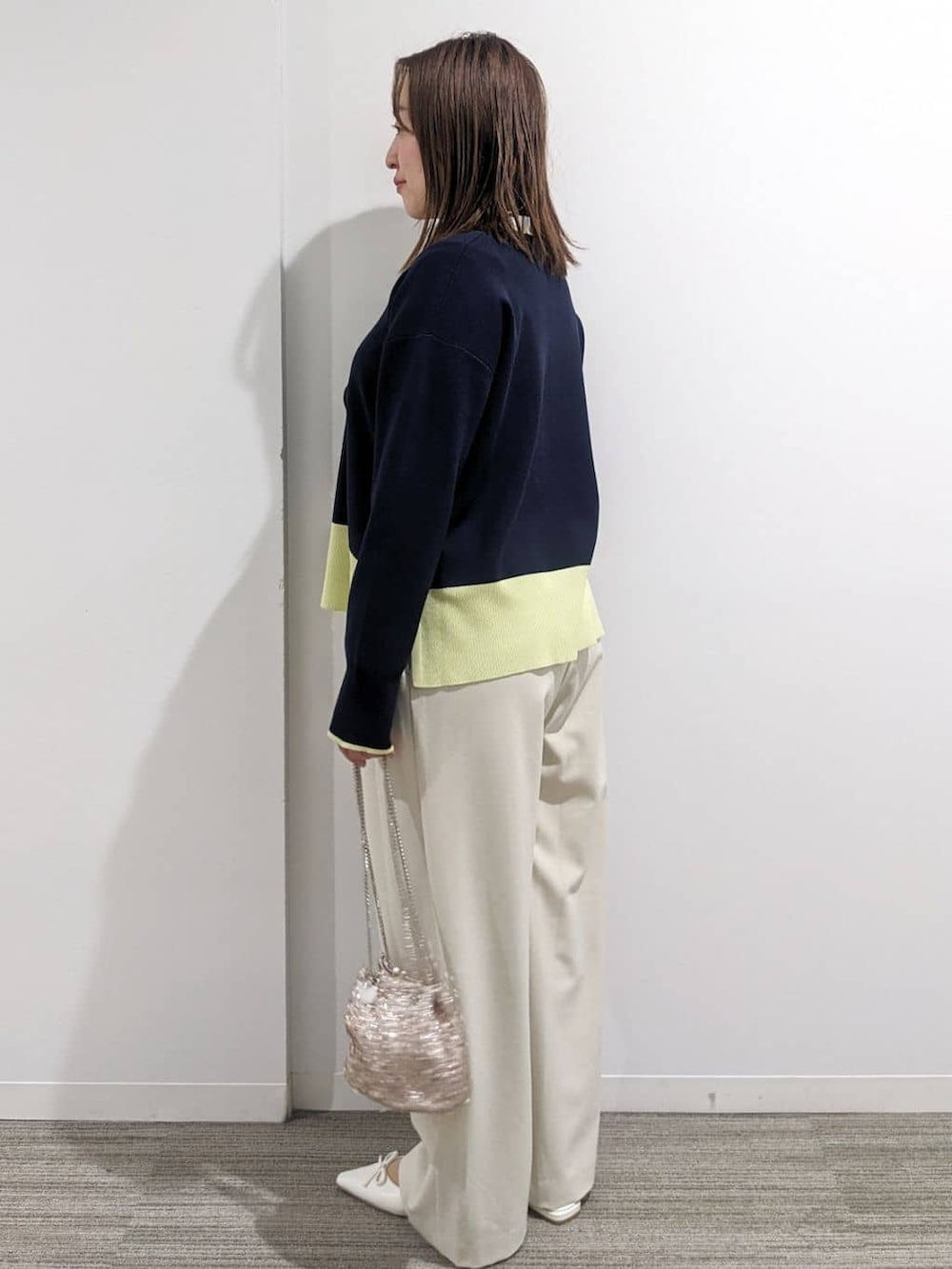 グレー系のノーカラーコート、ブルー系のニット/セーター、ホワイト系のTシャツ/カットソーを着用したレディースの春コーディネートの4枚目の写真