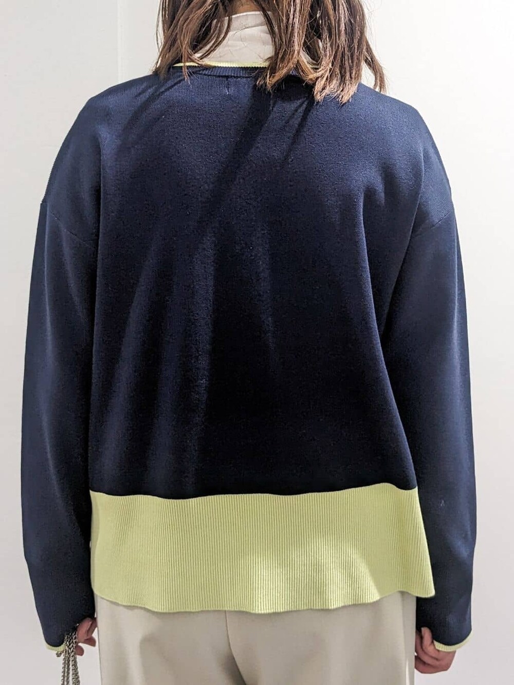 グレー系のノーカラーコート、ブルー系のニット/セーター、ホワイト系のTシャツ/カットソーを着用したレディースの春コーディネートの5枚目の写真