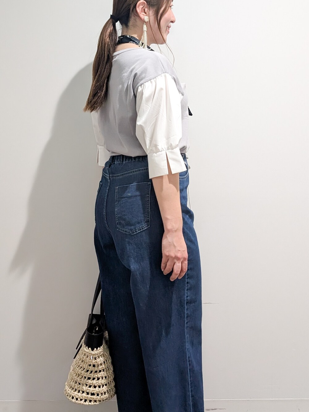 グレー系のニット/セーター、ブルー系のデニムパンツ、ブラック系のトートバッグを着用したレディースの夏コーディネートの5枚目の写真