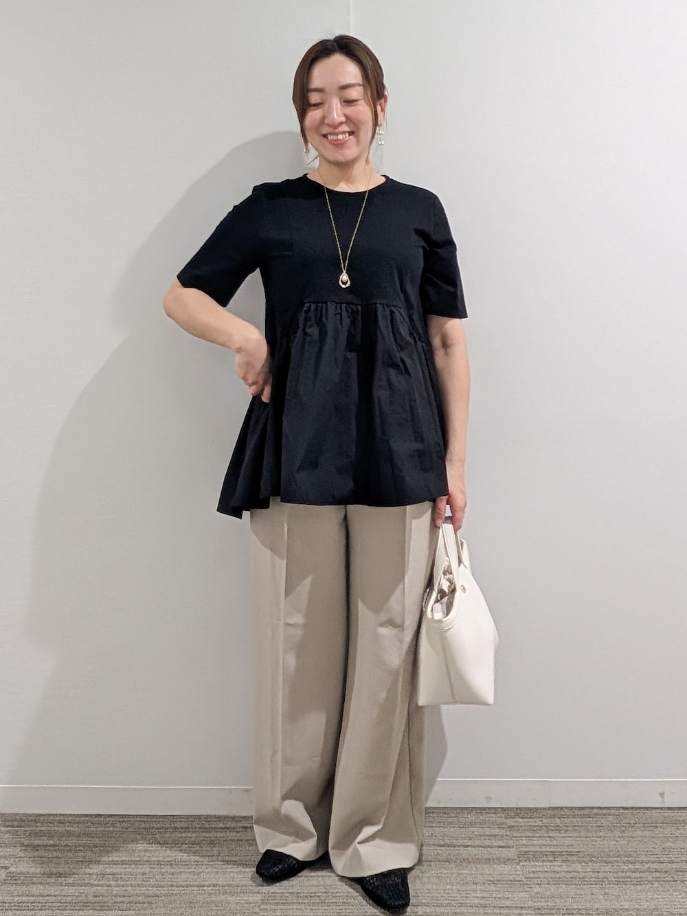 ブラック系のTシャツ/カットソー、ベージュ系のその他パンツ、ホワイト系のショルダーバッグを着用したレディースの春コーディネートの2枚目の写真