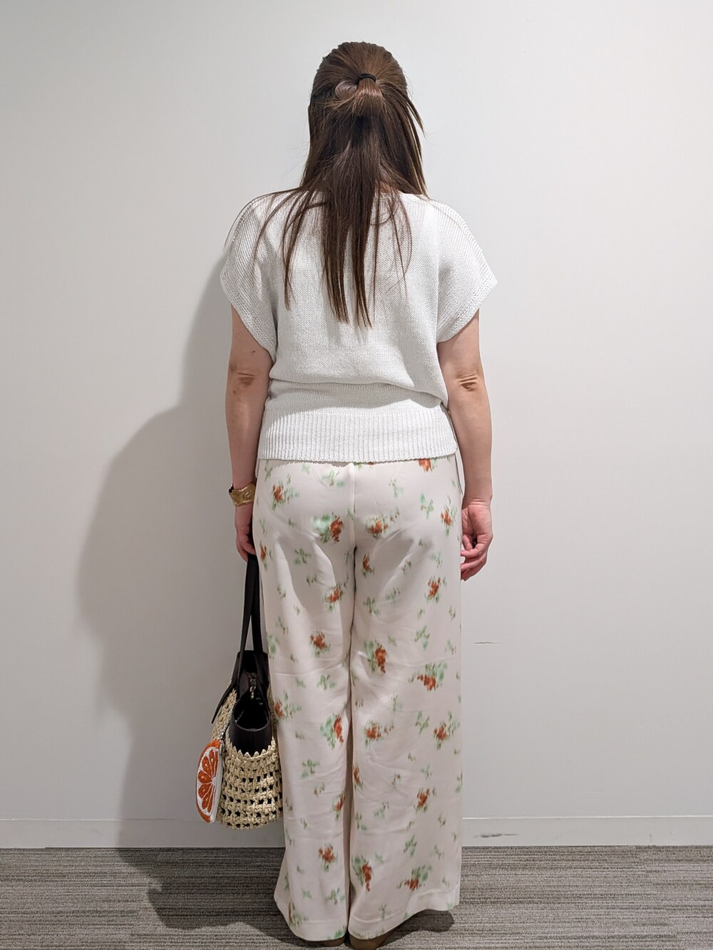 ホワイト系のニット/セーター、ホワイト系のその他パンツ、ブラウン系のトートバッグを着用したレディースの夏コーディネートの5枚目の写真