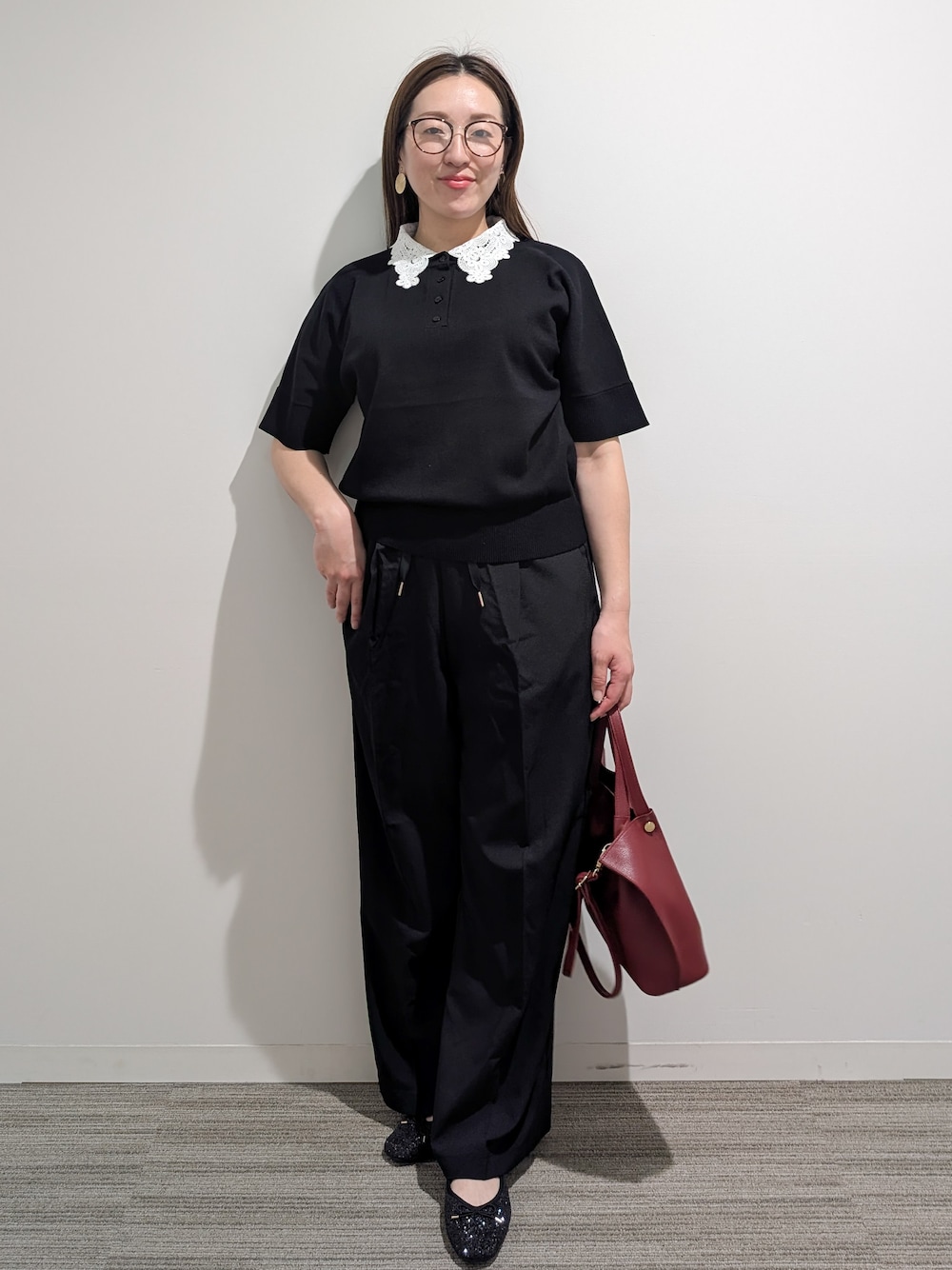 ブラック系のニット/セーター、ブラック系のその他パンツ、レッド系のショルダーバッグを着用したレディースの秋コーディネートの3枚目の写真