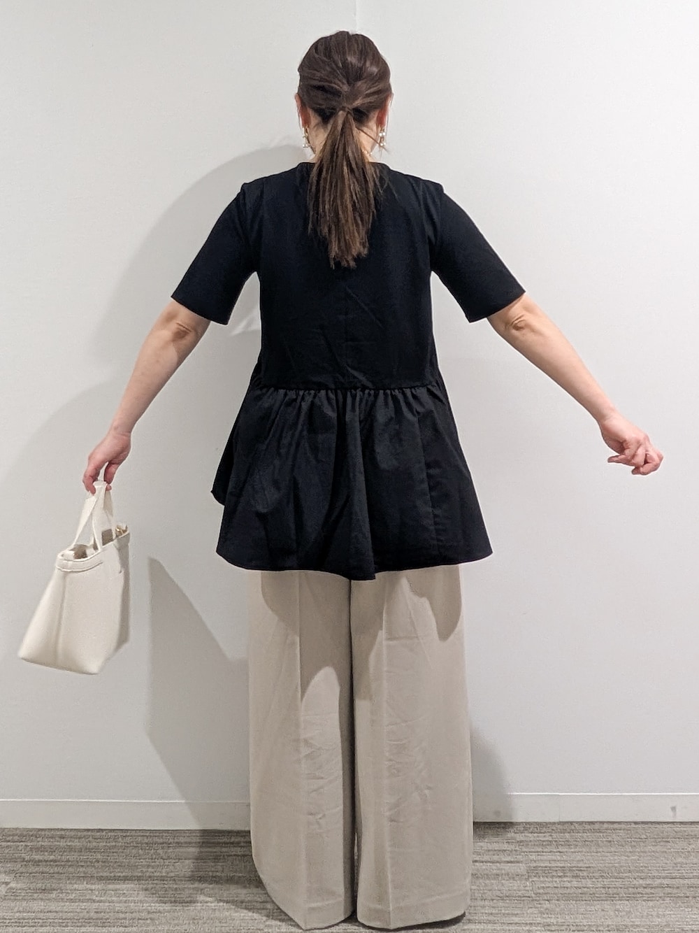 ブラック系のTシャツ/カットソー、ベージュ系のその他パンツ、ホワイト系のショルダーバッグを着用したレディースの春コーディネートの6枚目の写真
