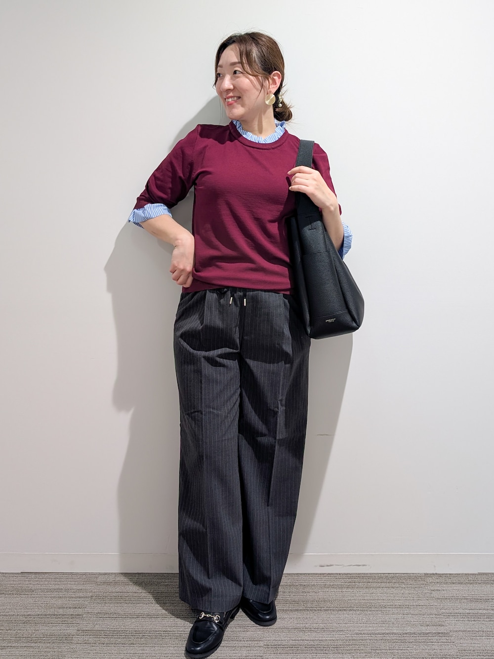 レッド系のニット/セーター、グレー系のその他パンツ、ブラック系のトートバッグを着用したレディースの秋コーディネートの7枚目の写真
