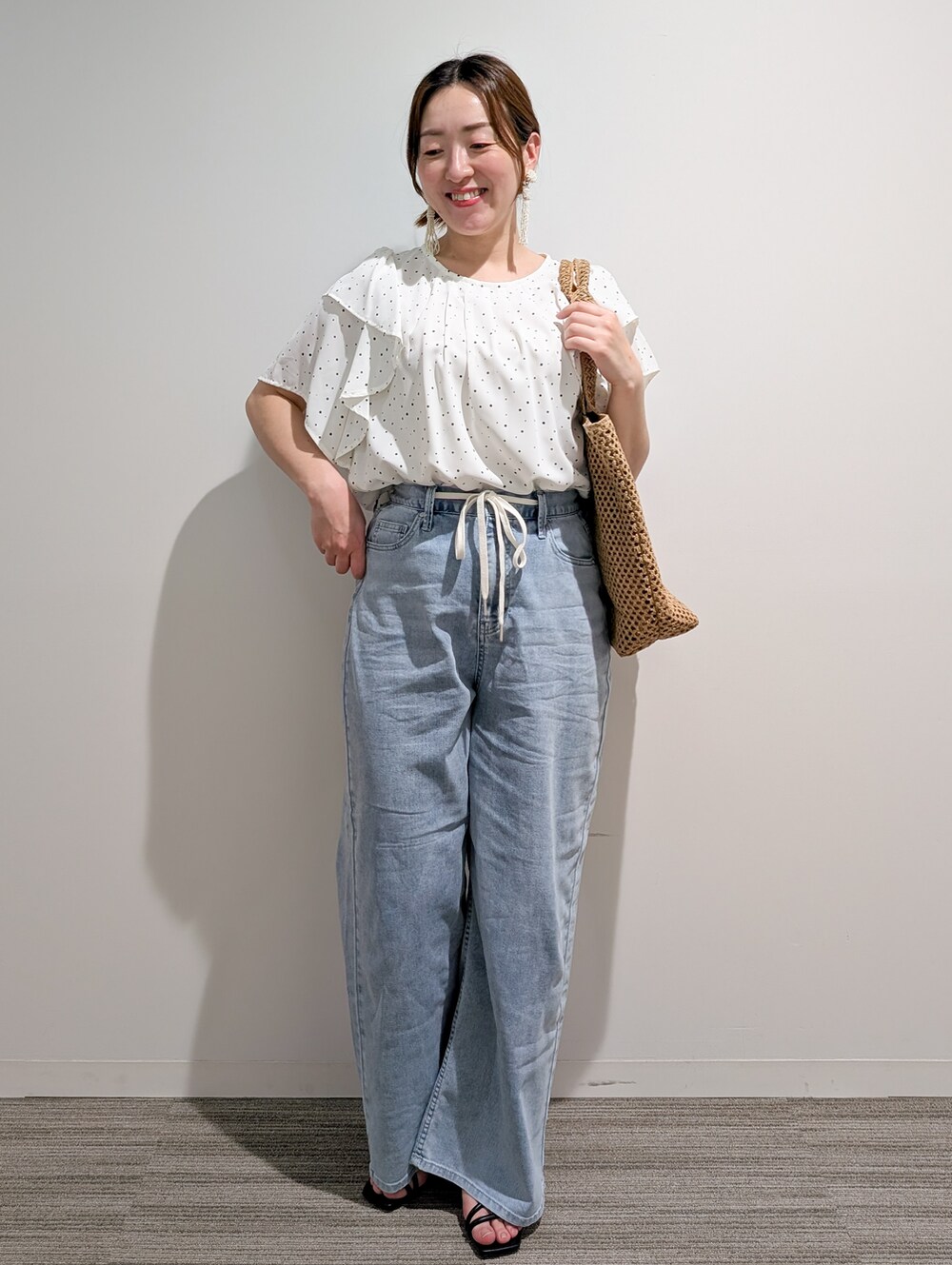 ホワイト系のシャツ/ブラウス、ブラック系のサンダル、ベージュ系のトートバッグを着用したレディースの春コーディネートの2枚目の写真