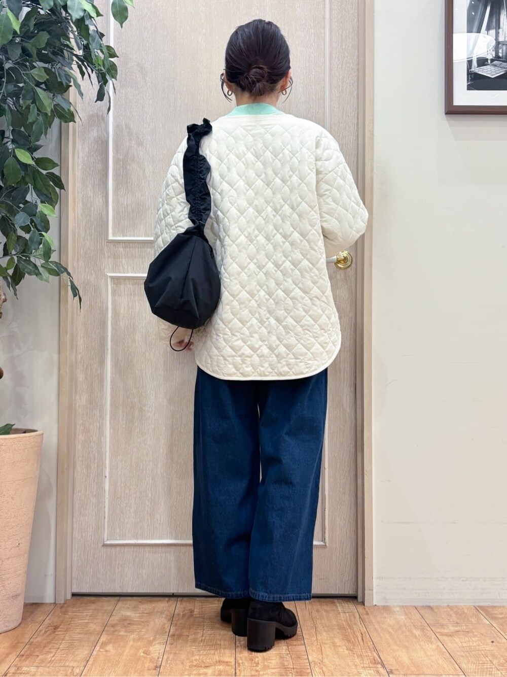 ホワイト系のノーカラージャケット、グリーン系のニット/セーター、ブルー系のデニムパンツを着用したレディースの冬コーディネートの3枚目の写真