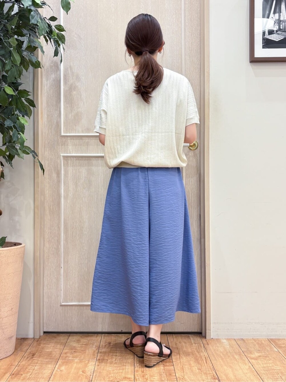 ゴールド系のニット/セーター、ブルー系のその他パンツ、ブラック系のサンダルを着用したレディースの夏コーディネートの3枚目の写真