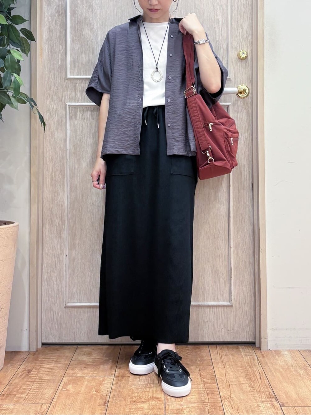 ブラウン系のシャツ/ブラウス、ホワイト系のTシャツ/カットソー、ブラック系のスカートを着用したレディースの秋コーディネートの4枚目の写真