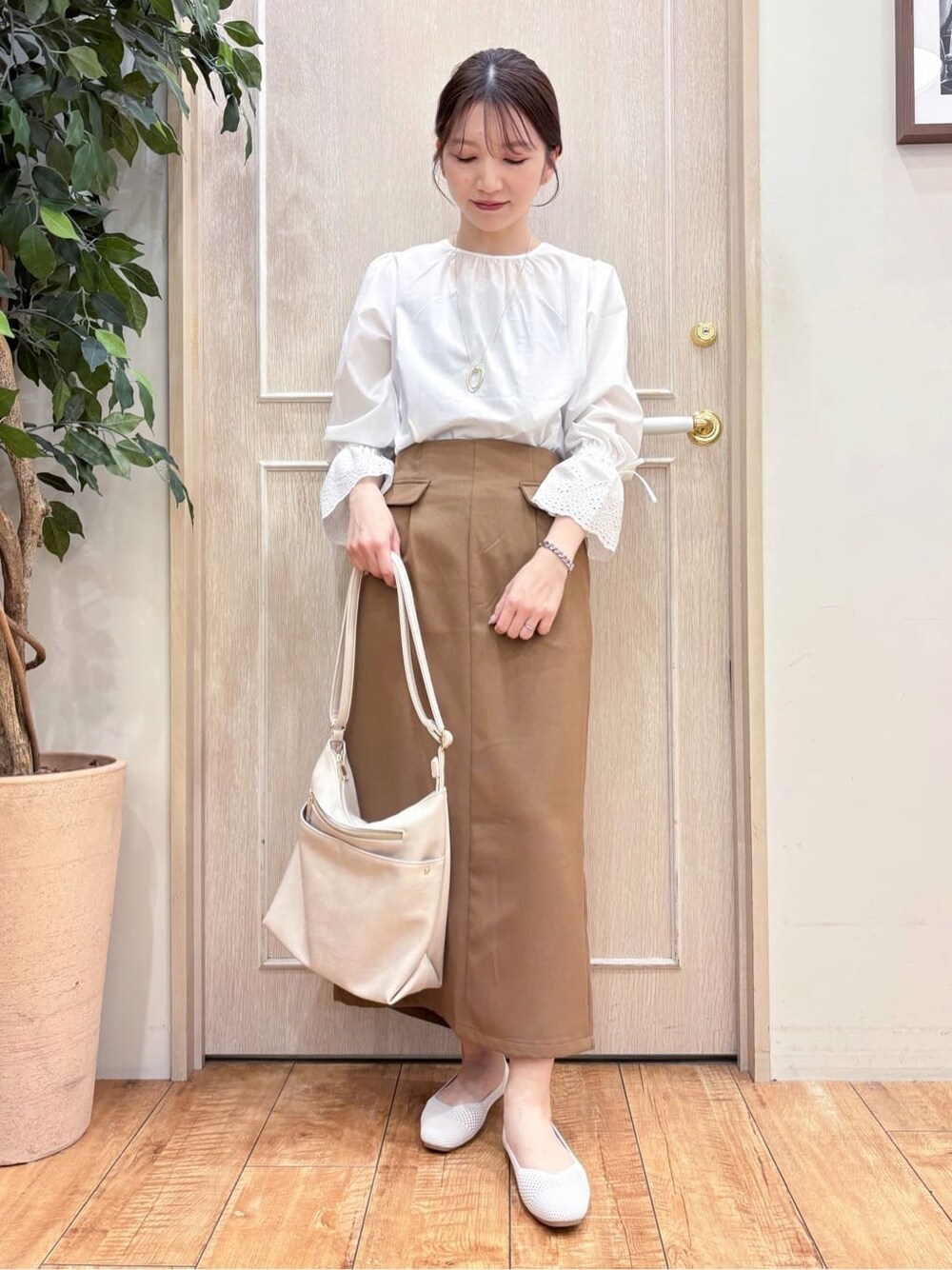 ホワイト系のシャツ/ブラウス、ブラウン系のスカート、ホワイト系のパンプスを着用したレディースの春コーディネートの2枚目の写真