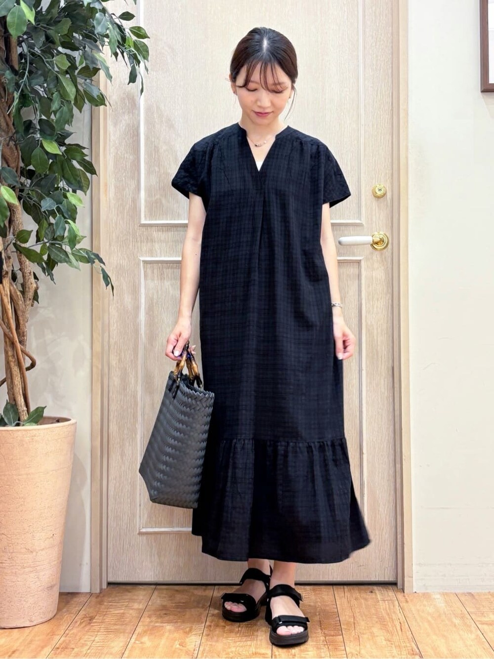 ブラック系のワンピース、ブラック系のサンダル、ブラック系のトートバッグを着用したレディースの夏コーディネートの2枚目の写真