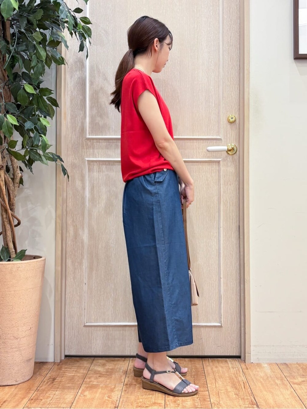 レッド系のニット/セーター、ブルー系のデニムパンツ、グレー系のサンダルを着用したレディースの夏コーディネートの2枚目の写真