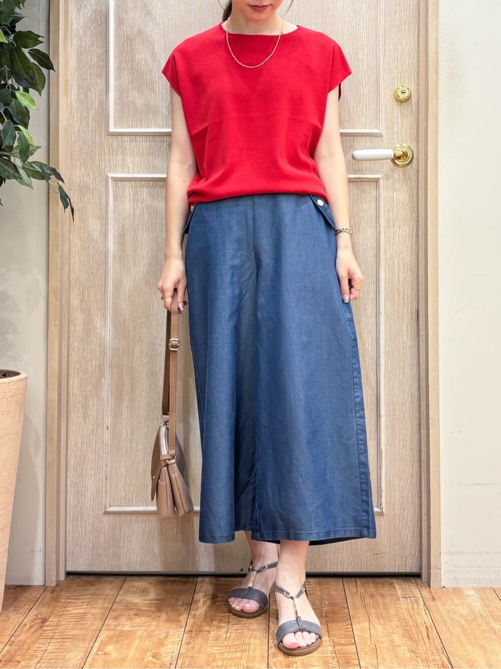 レッド系のニット/セーター、ブルー系のデニムパンツ、グレー系のサンダルを着用したレディースの夏コーディネートの4枚目の写真
