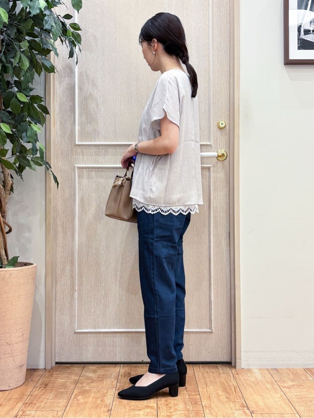 ベージュ系のTシャツ/カットソー、ブルー系のデニムパンツ、ブラック系のパンプスを着用したレディースの夏コーディネートの2枚目の写真