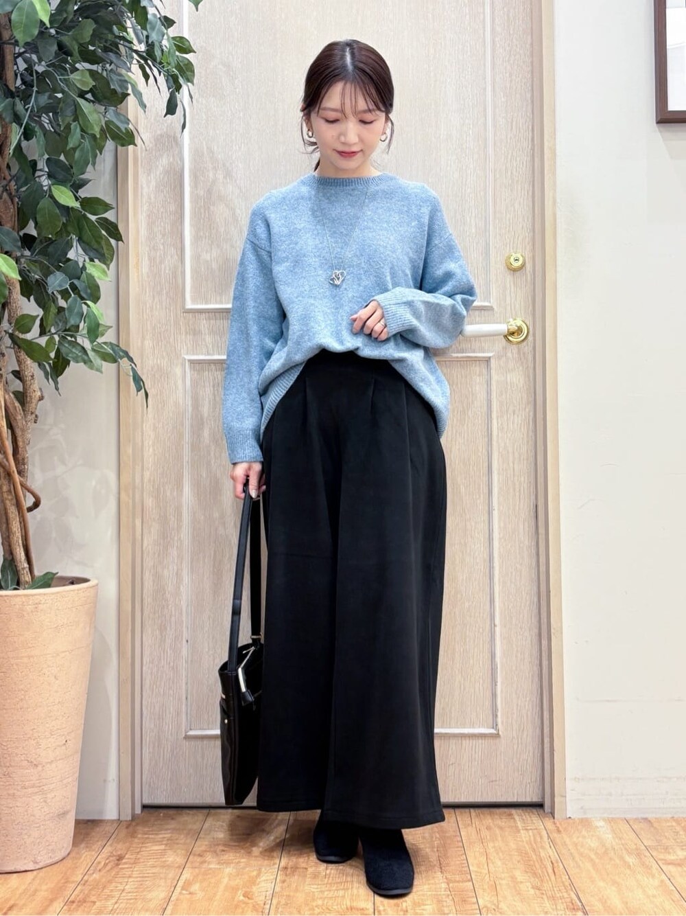 グレー系のチェスターコート、ブルー系のニット/セーター、ブラック系のその他パンツを着用したレディースの冬コーディネートの6枚目の写真