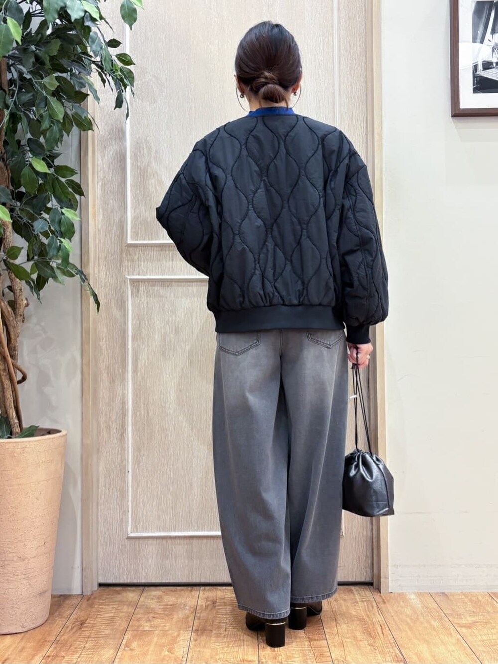 ブラック系のブルゾン、ブルー系のニット/セーター、ブラック系のデニムパンツを着用したレディースの秋コーディネートの4枚目の写真
