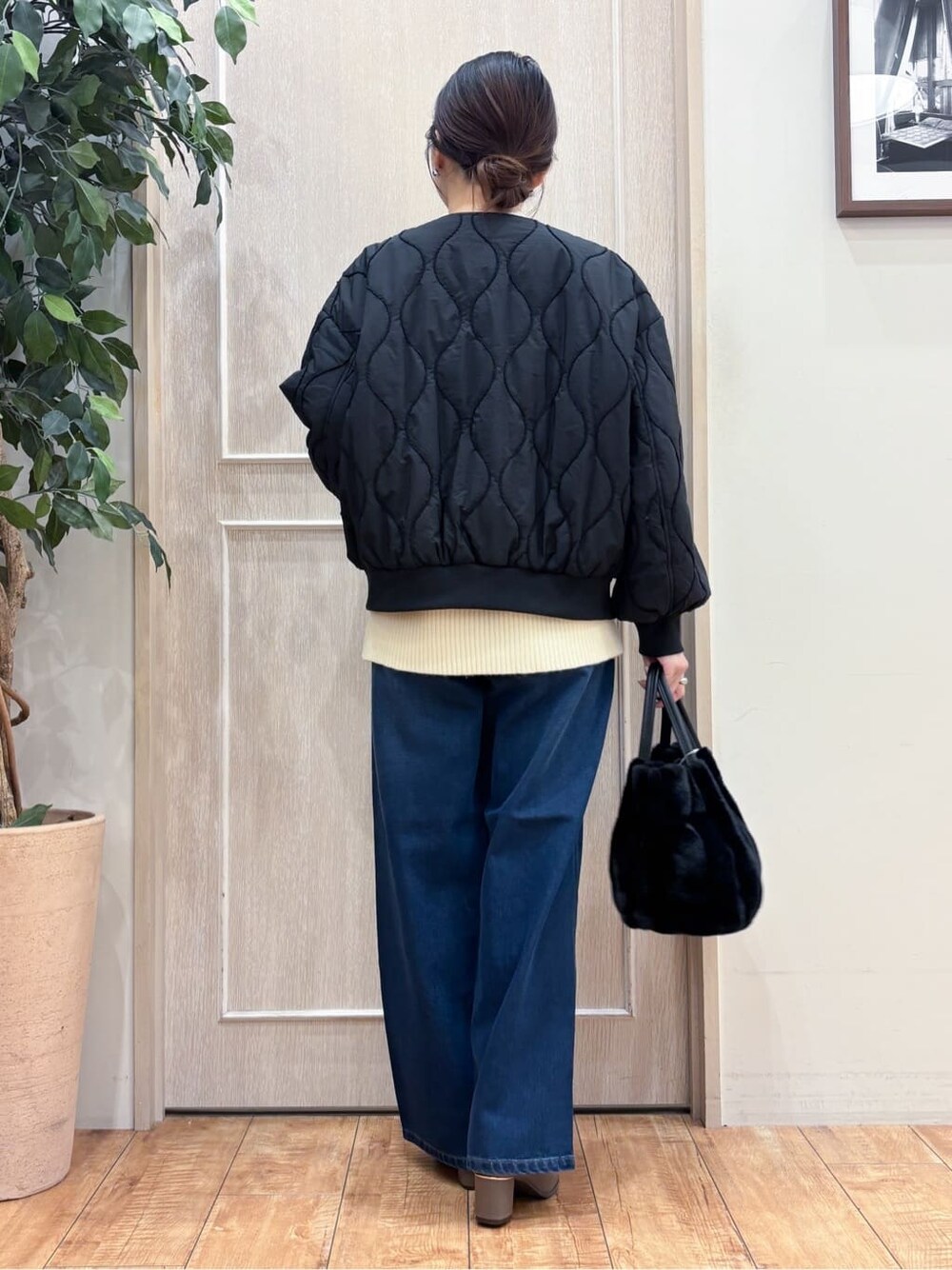 ブラック系のブルゾン、ベージュ系のニット/セーター、ブルー系のデニムパンツを着用したレディースの冬コーディネートの3枚目の写真