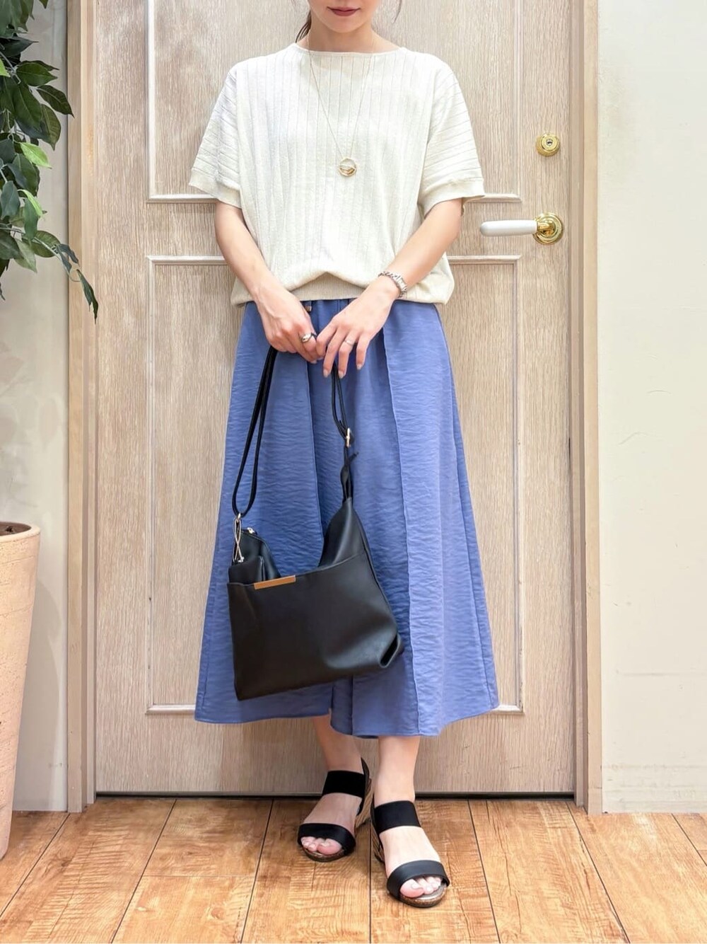 ゴールド系のニット/セーター、ブルー系のその他パンツ、ブラック系のサンダルを着用したレディースの夏コーディネートの4枚目の写真