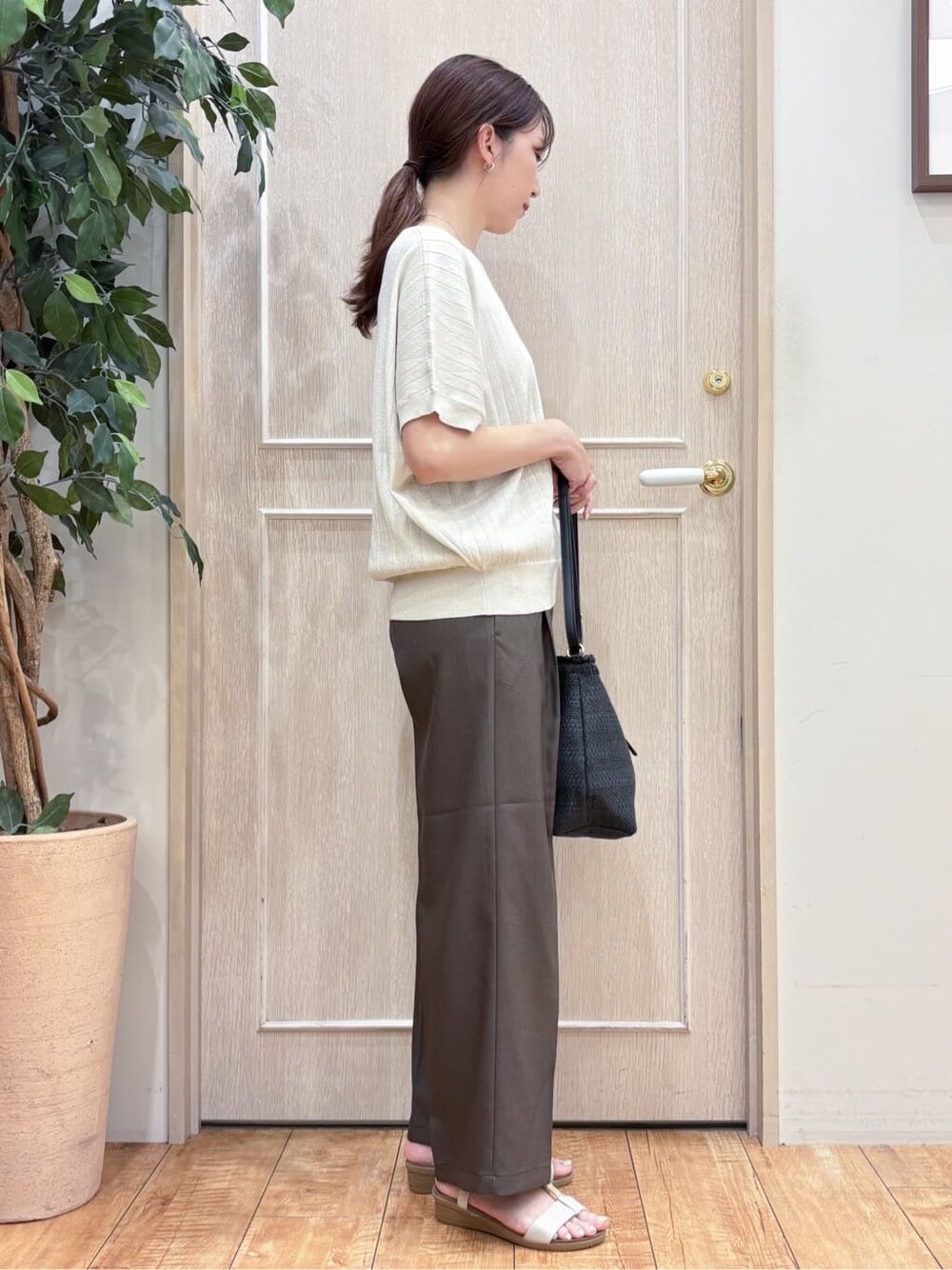 ゴールド系のニット/セーター、ブラウン系のその他パンツ、ゴールド系のサンダルを着用したレディースの夏コーディネートの2枚目の写真