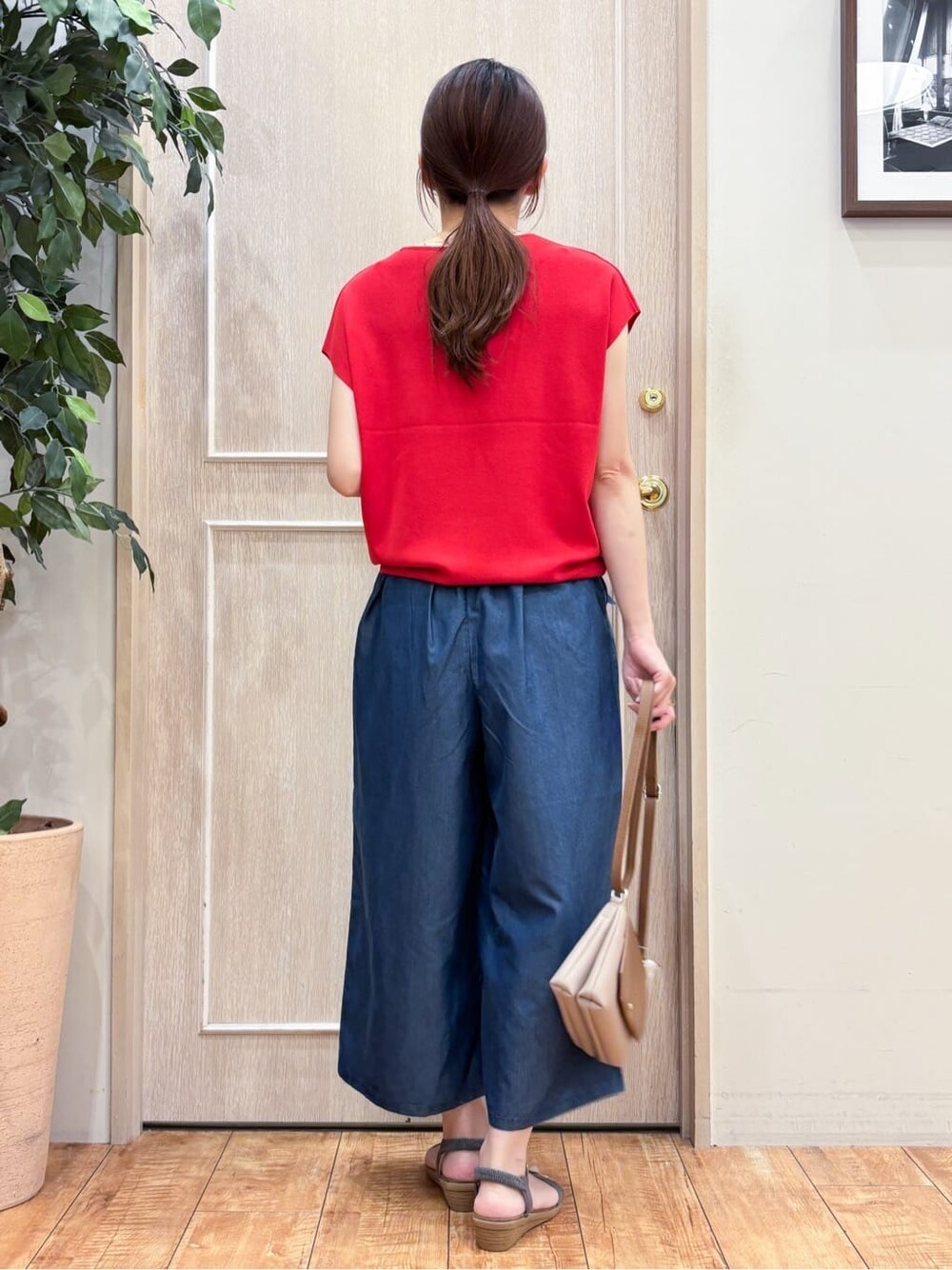レッド系のニット/セーター、ブルー系のデニムパンツ、グレー系のサンダルを着用したレディースの夏コーディネートの3枚目の写真