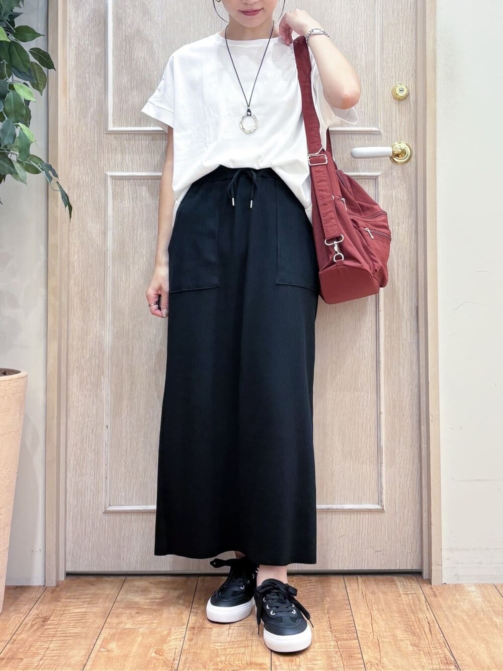 ブラウン系のシャツ/ブラウス、ホワイト系のTシャツ/カットソー、ブラック系のスカートを着用したレディースの秋コーディネートの5枚目の写真