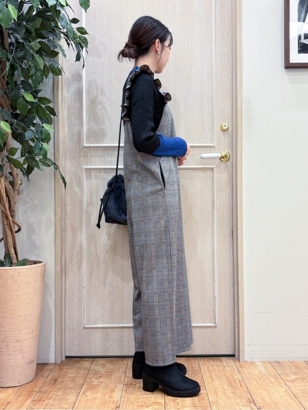 グレー系のサロペット/オーバーオール、ブルー系のニット/セーター、ブラック系のブーツを着用したレディースの秋コーディネートの2枚目の写真