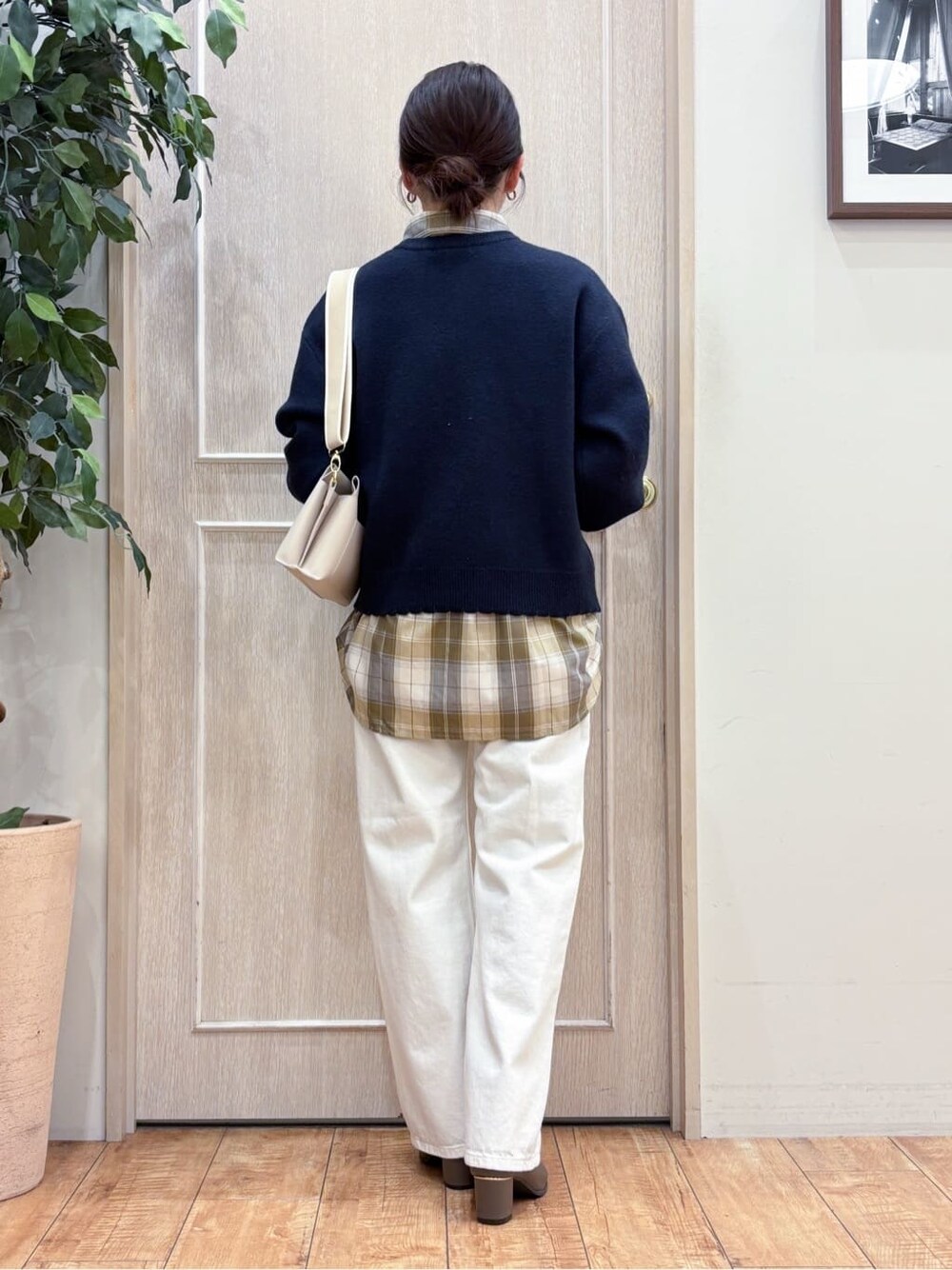 ブルー系のニット/セーター、ベージュ系のシャツ/ブラウス、ホワイト系のデニムパンツを着用したレディースの冬コーディネートの3枚目の写真