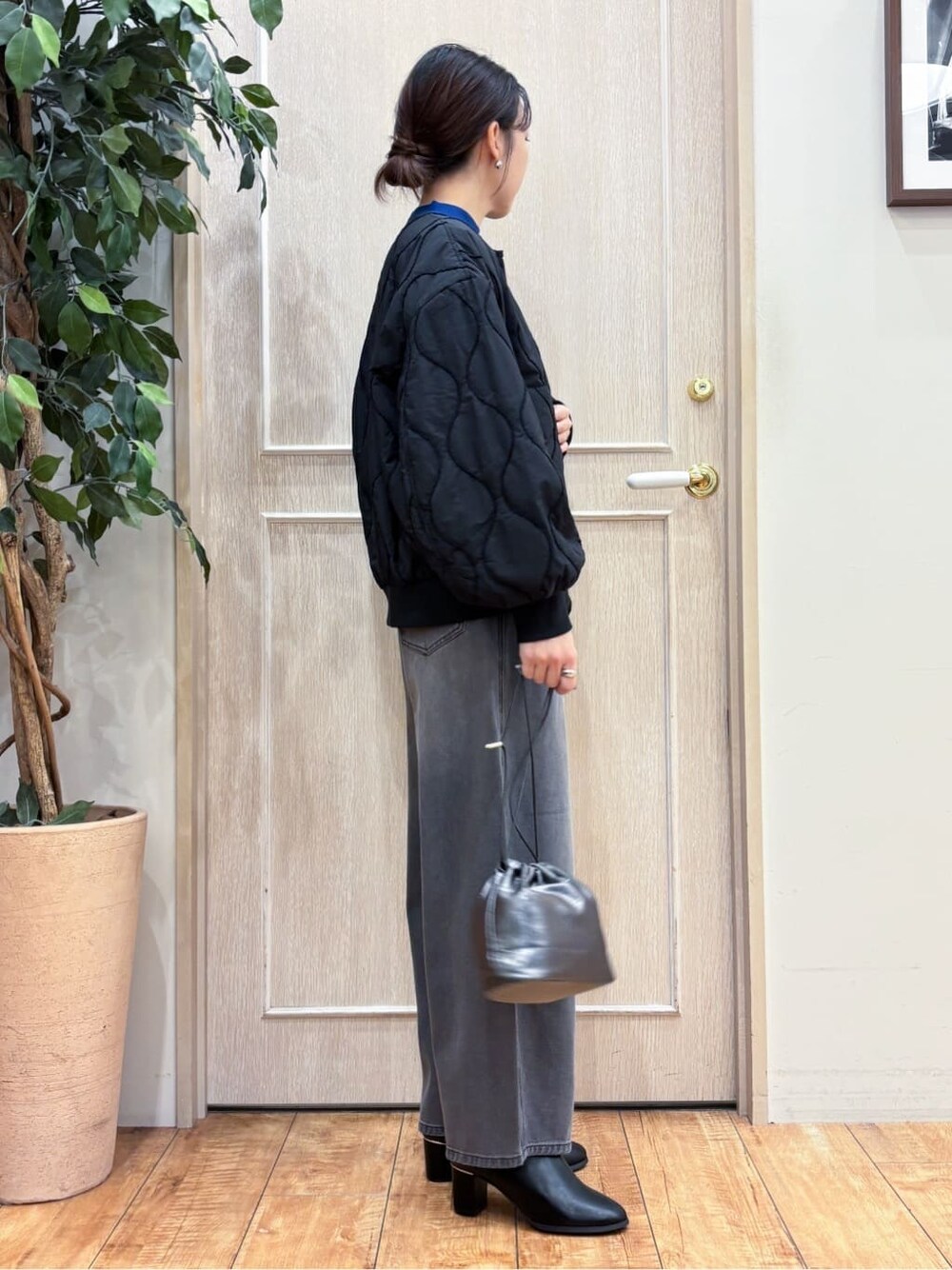 ブラック系のブルゾン、ブルー系のニット/セーター、ブラック系のデニムパンツを着用したレディースの秋コーディネートの3枚目の写真