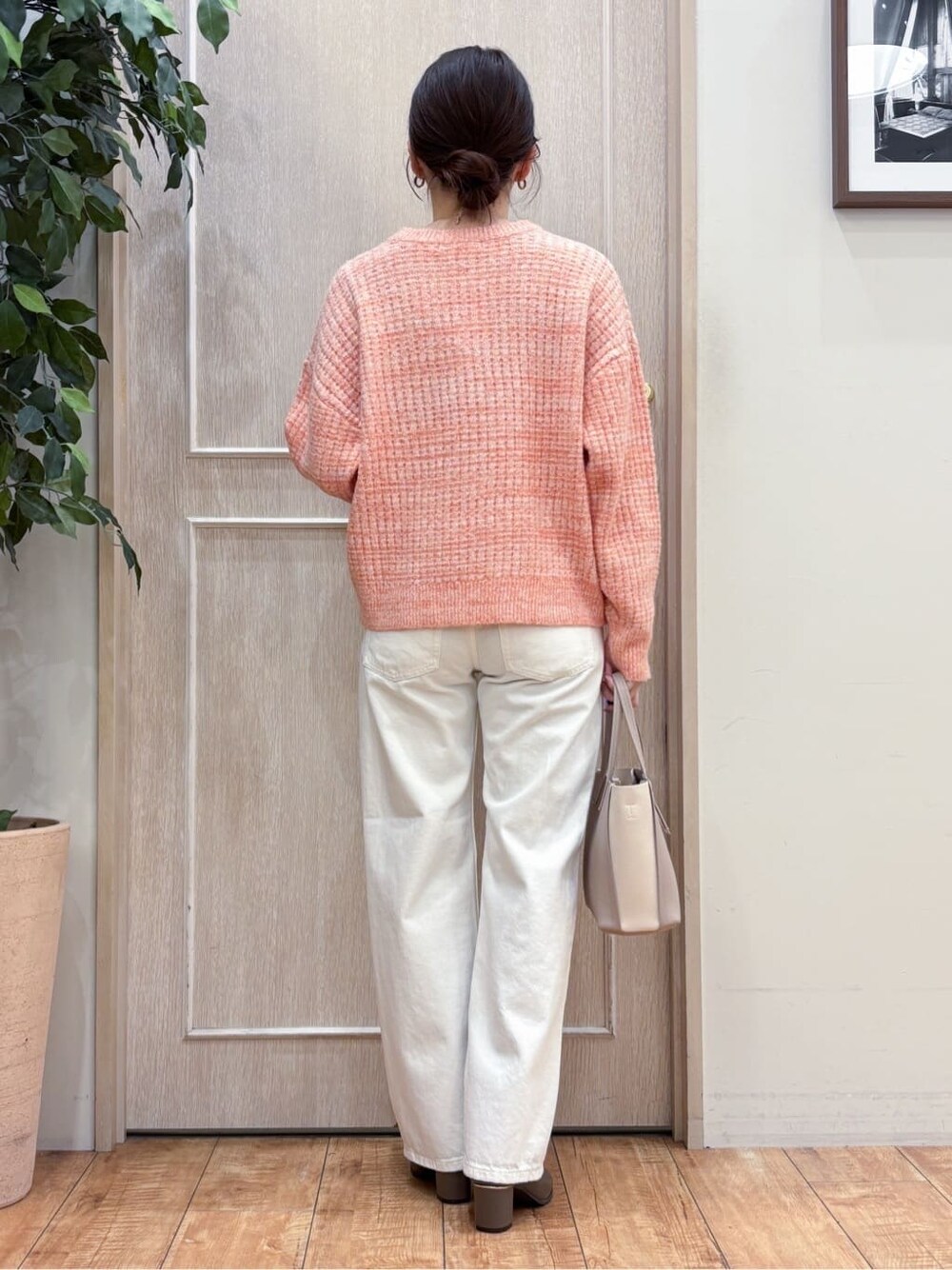 オレンジ系のニット/セーター、ホワイト系のデニムパンツ、ブラウン系のブーツを着用したレディースの冬コーディネートの3枚目の写真