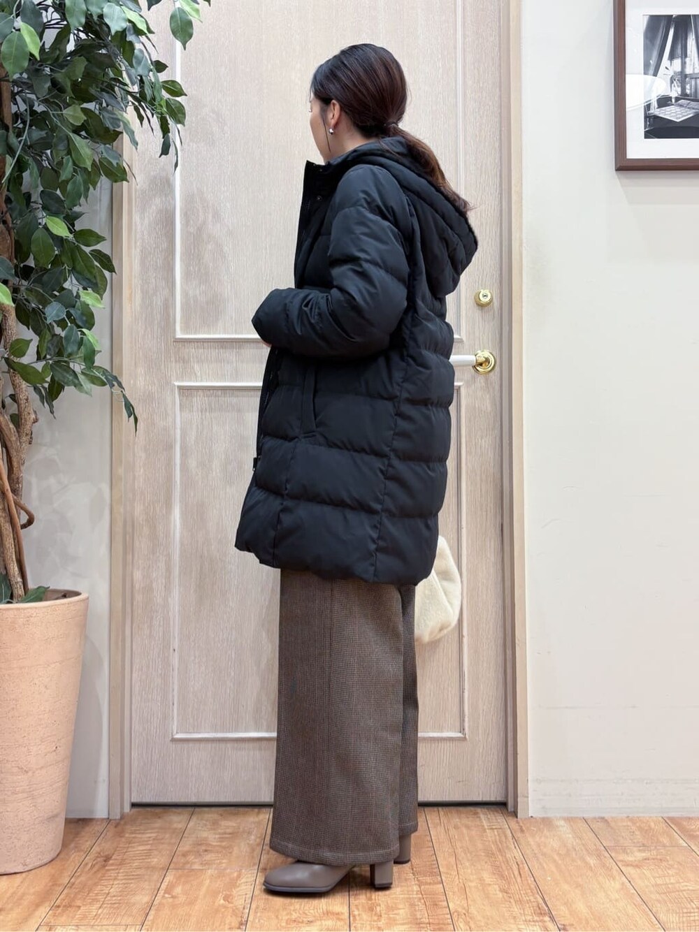 ブラック系のダウンジャケット/コート、ブルー系のニット/セーター、ベージュ系のその他パンツを着用したレディースの冬コーディネートの2枚目の写真