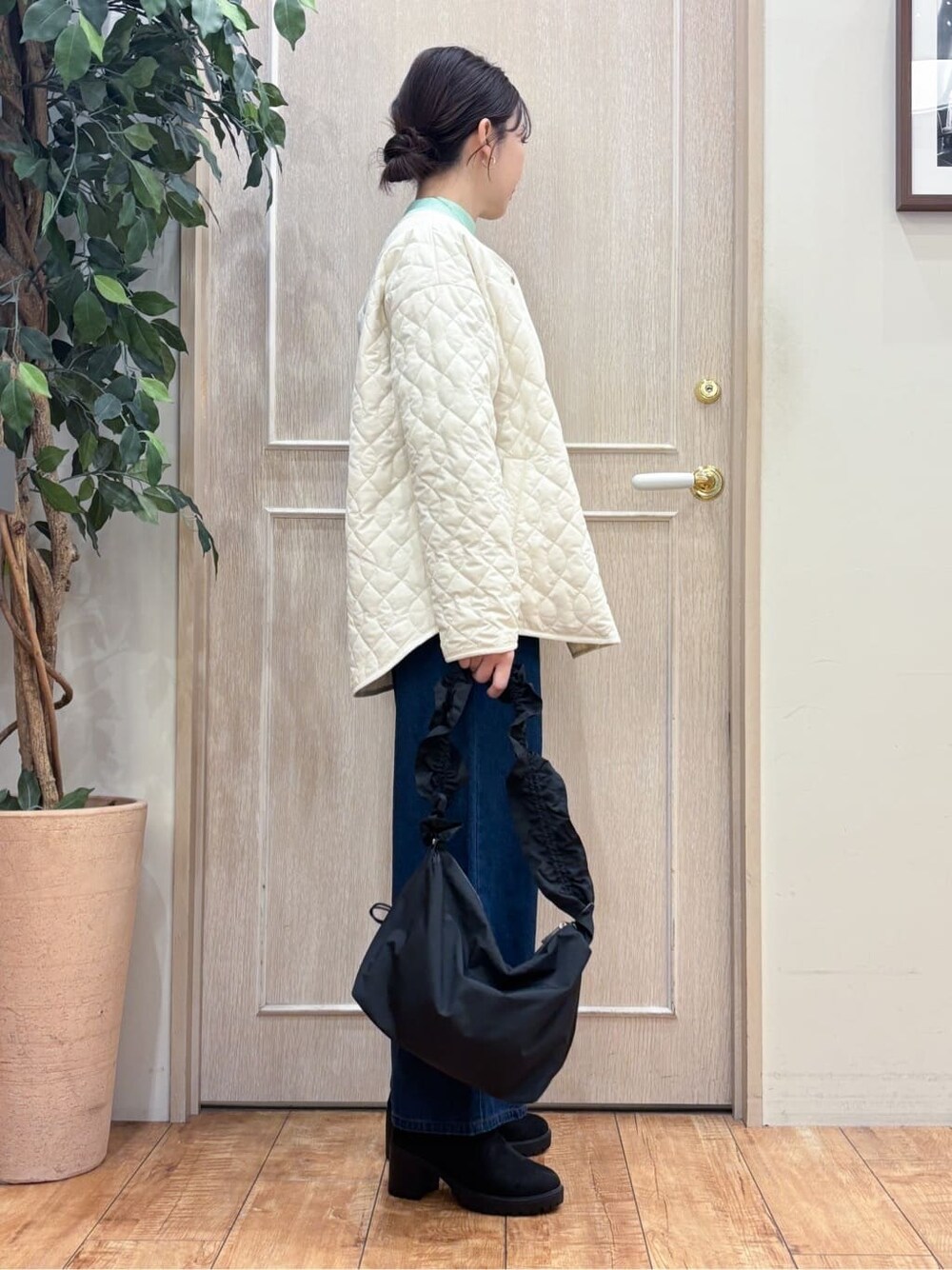 ホワイト系のノーカラージャケット、グリーン系のニット/セーター、ブルー系のデニムパンツを着用したレディースの冬コーディネートの2枚目の写真