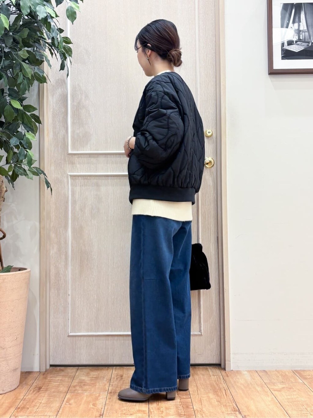ブラック系のブルゾン、ベージュ系のニット/セーター、ブルー系のデニムパンツを着用したレディースの冬コーディネートの2枚目の写真