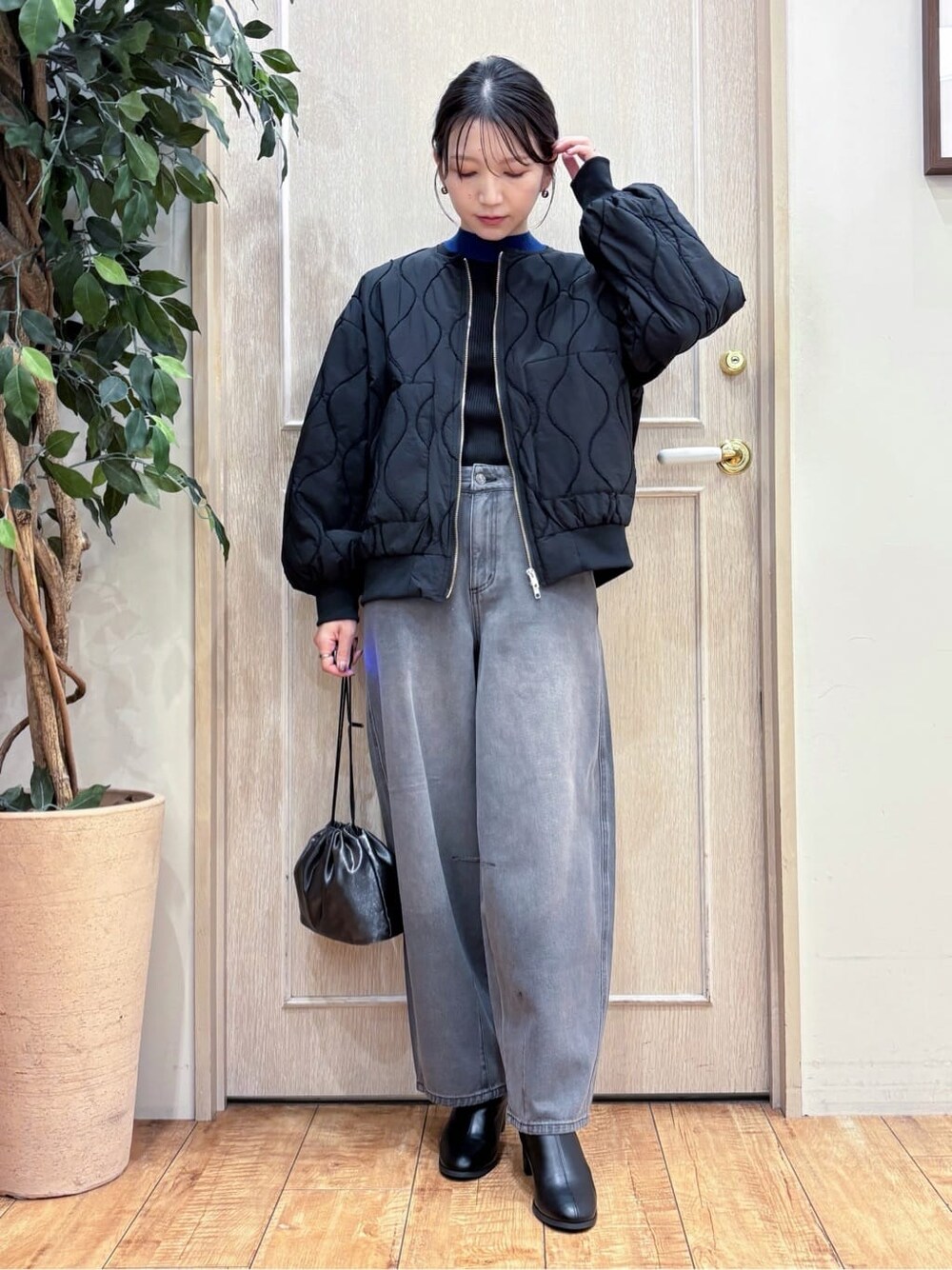 ブラック系のブルゾン、ブルー系のニット/セーター、ブラック系のデニムパンツを着用したレディースの秋コーディネートの2枚目の写真