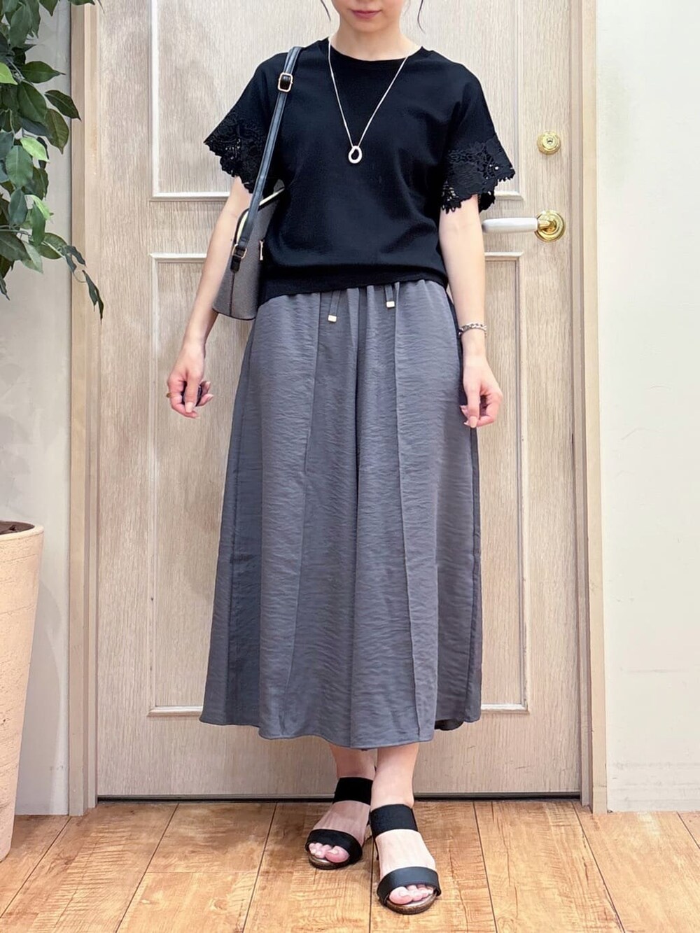 ブラック系のニット/セーター、グレー系のその他パンツ、ブラック系のサンダルを着用したレディースの夏コーディネートの4枚目の写真