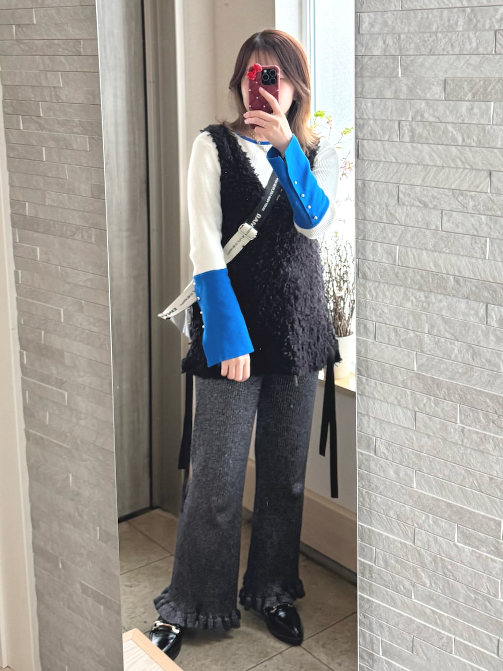 ブラック系のベスト、ブラック系のパンツを着用したレディースの冬コーディネートの2枚目の写真