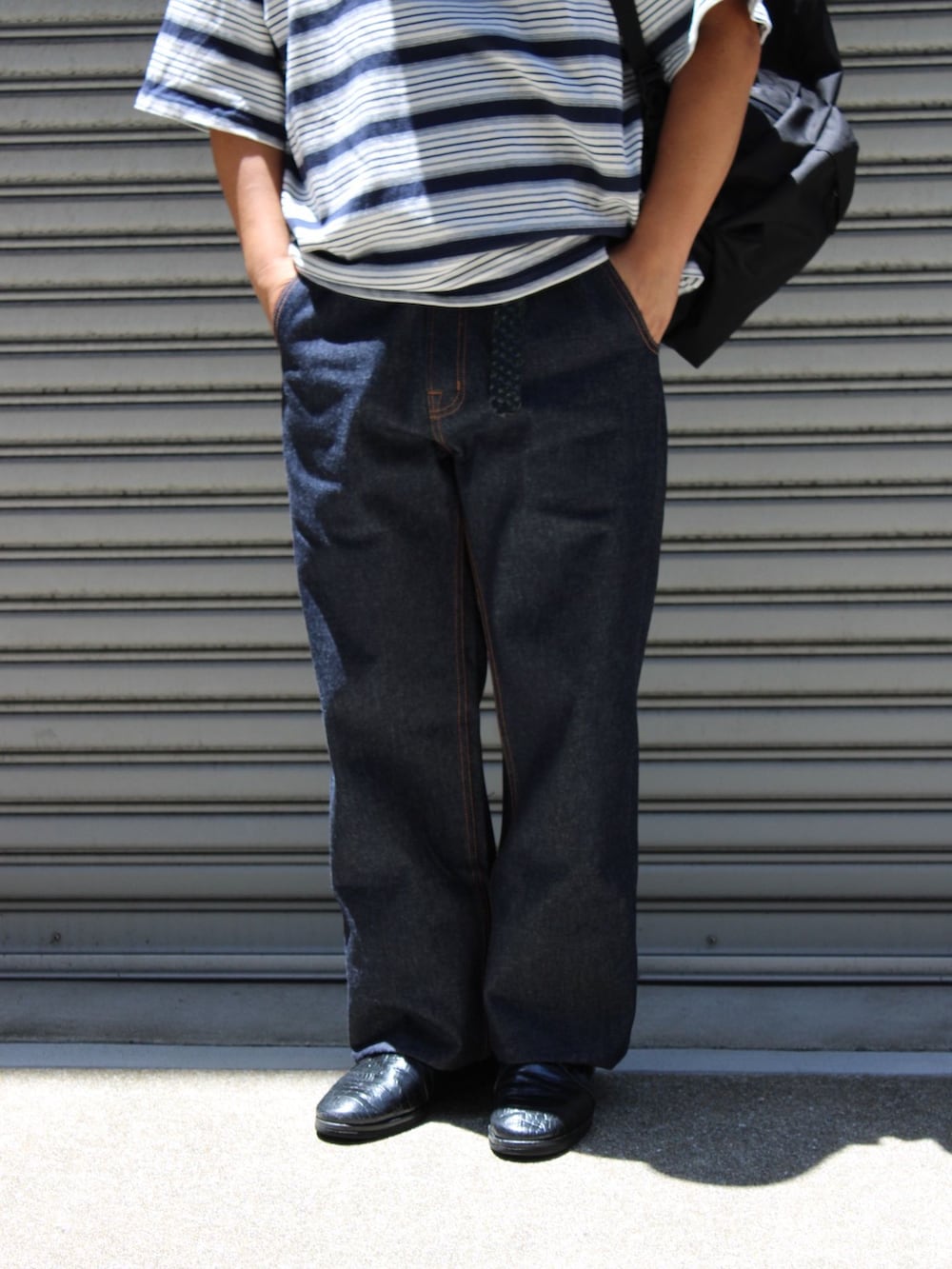 ブルー系のデニムパンツ、ブルー系のTシャツ/カットソー、ブラック系のバックパック/リュックを着用したメンズの夏コーディネートの2枚目の写真