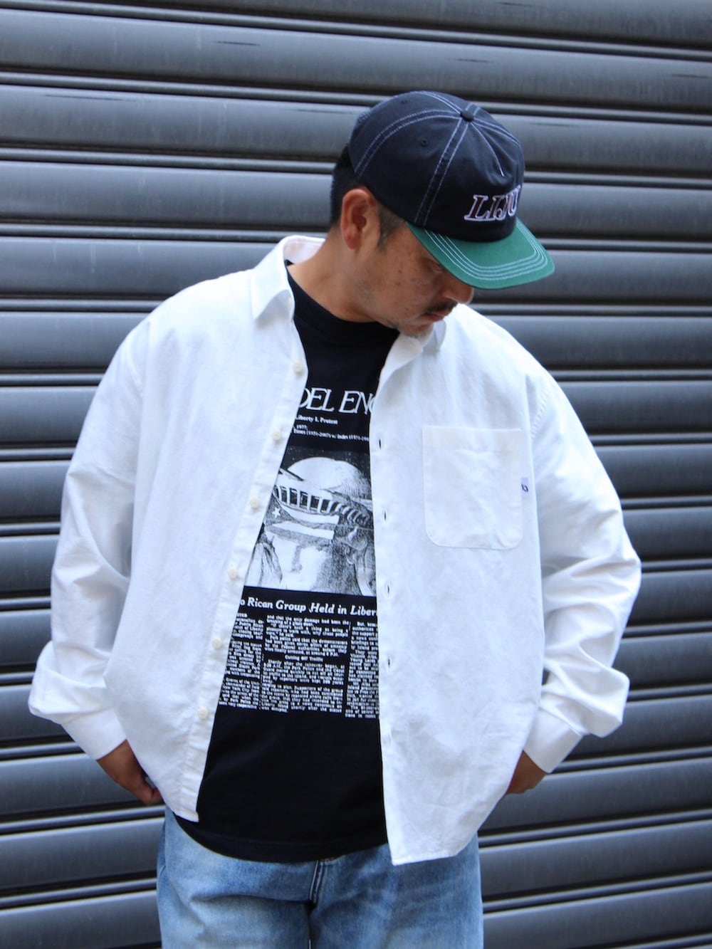 ブルー系のデニムパンツ、ホワイト系のシャツ/ブラウス、ブラック系のTシャツ/カットソーを着用したメンズの夏コーディネートの3枚目の写真