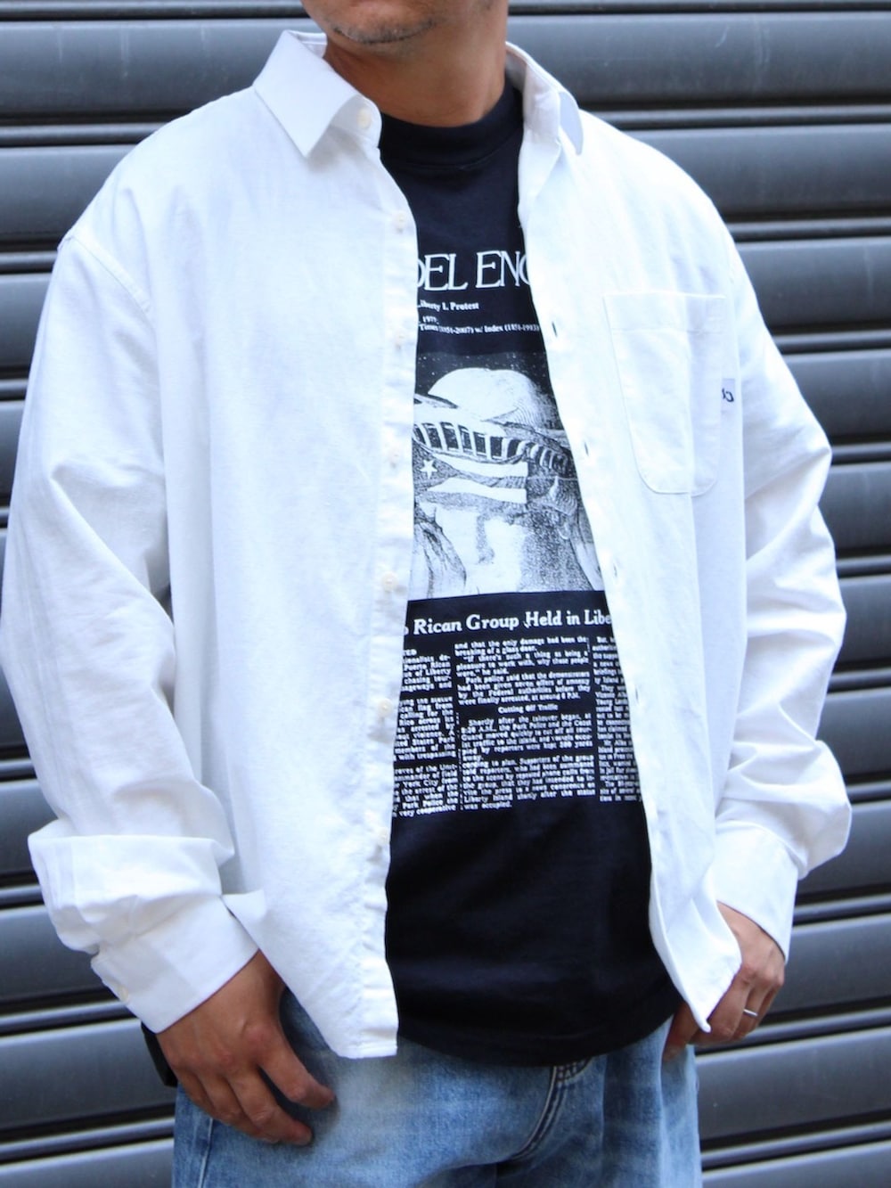 ブルー系のデニムパンツ、ホワイト系のシャツ/ブラウス、ブラック系のTシャツ/カットソーを着用したメンズの夏コーディネートの2枚目の写真
