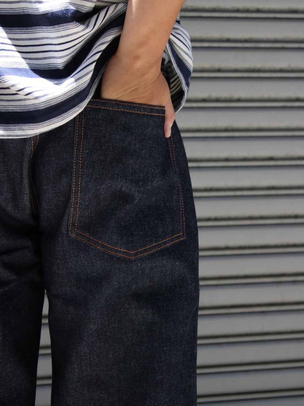 ブルー系のデニムパンツ、ブルー系のTシャツ/カットソー、ブラック系のバックパック/リュックを着用したメンズの夏コーディネートの4枚目の写真