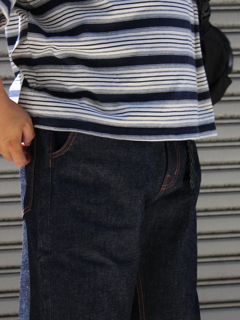 ブルー系のデニムパンツ、ブルー系のTシャツ/カットソー、ブラック系のバックパック/リュックを着用したメンズの夏コーディネートの3枚目の写真