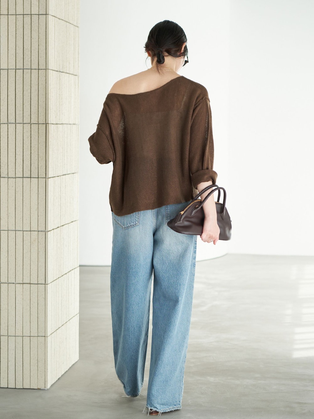 ブルー系のデニムパンツ、ブラウン系のニット/セーター、ゴールド系のネックレスを着用したレディースの春コーディネートの3枚目の写真