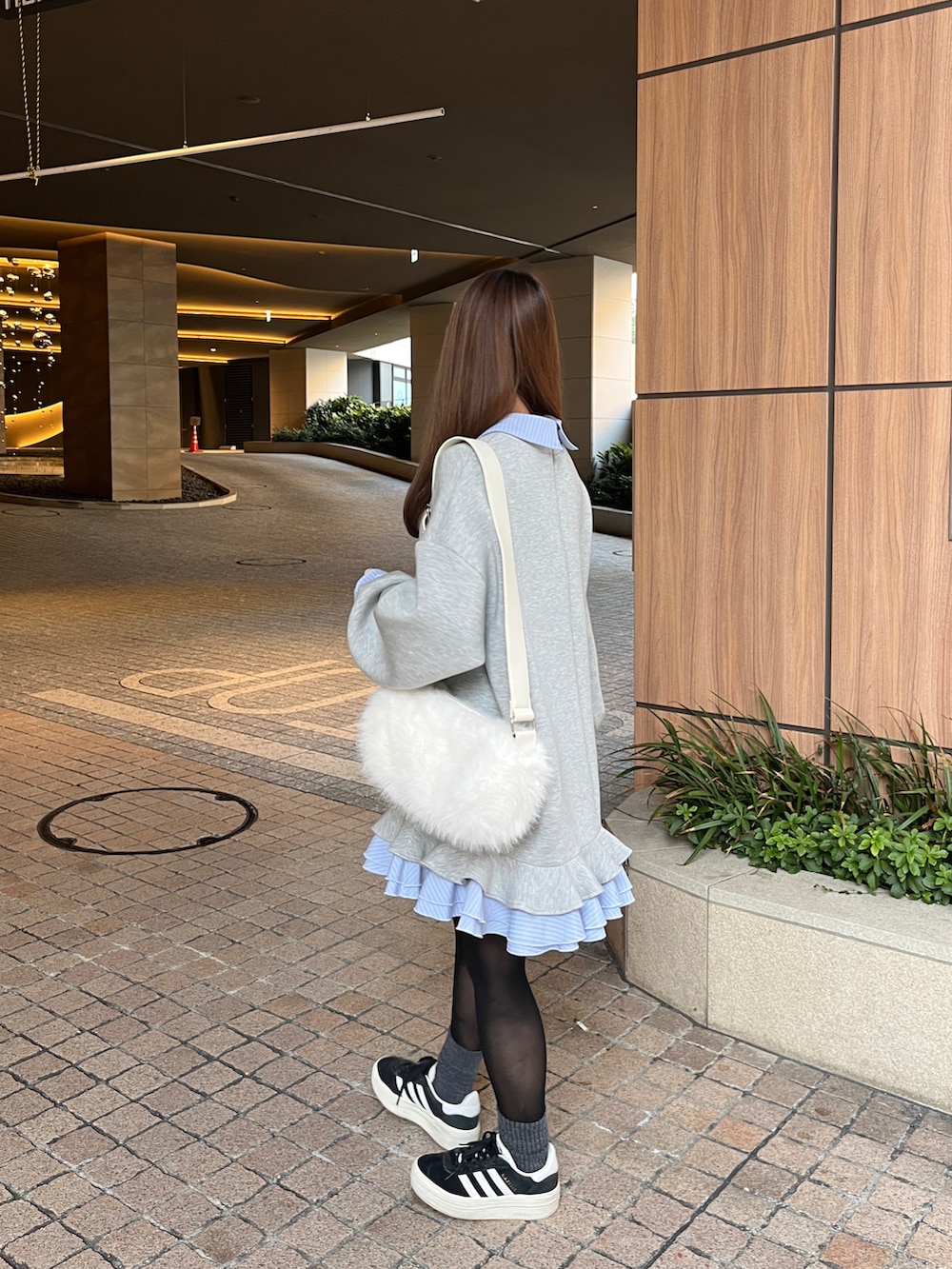 ブラック系のスニーカー、グレー系のスウェット、ホワイト系のショルダーバッグを着用したレディースの冬コーディネートの2枚目の写真