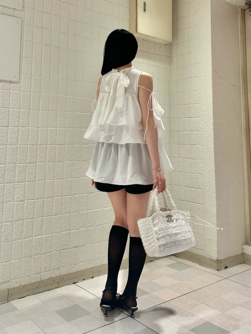 ホワイト系のシャツ/ブラウス、ブラック系のパンプス、ホワイト系のかごバッグを着用したレディースの夏コーディネートの4枚目の写真