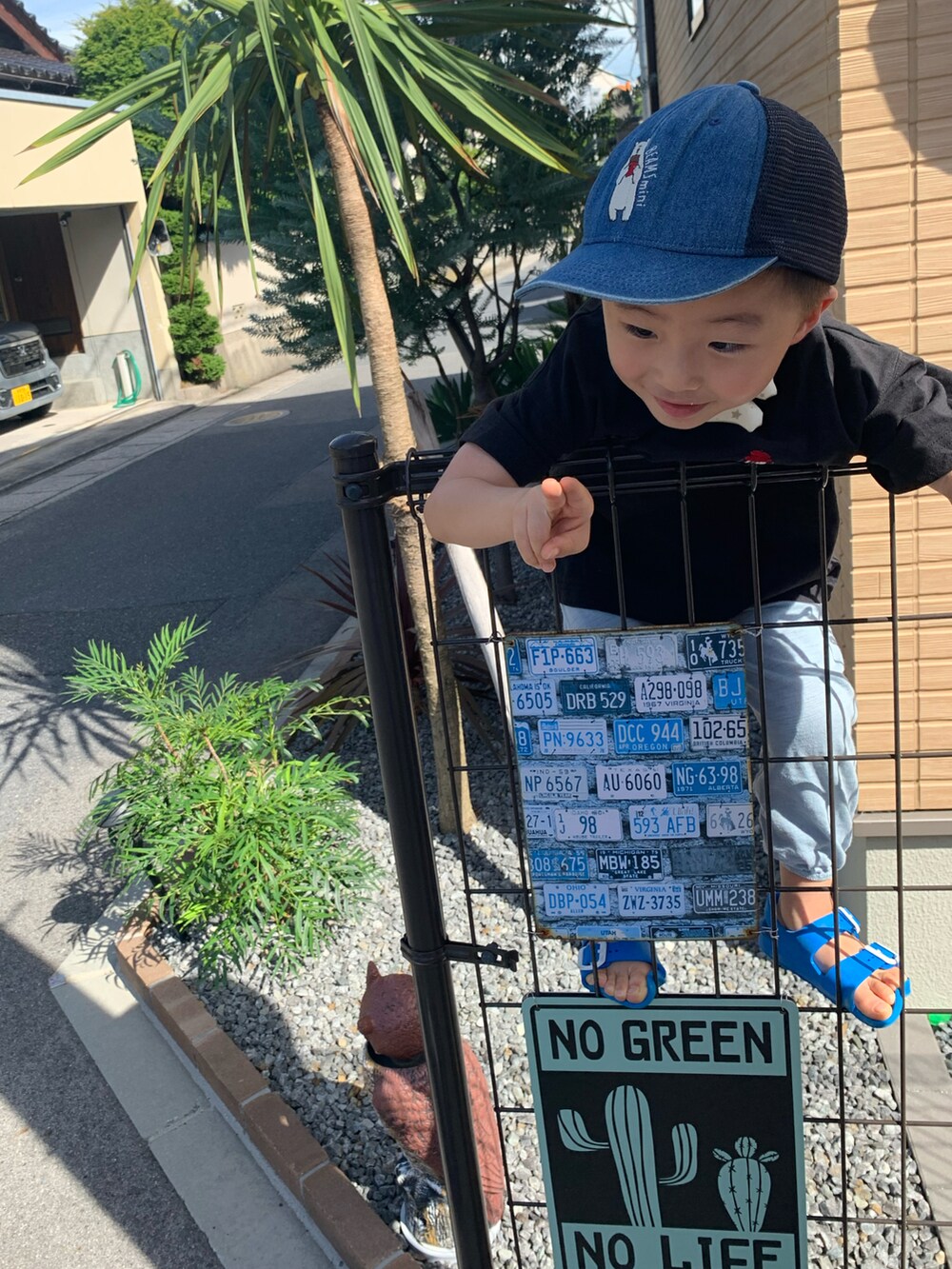 ブラック系のTシャツ/カットソー、ブルー系のサンダル、ブルー系のキャップを着用したメンズの夏コーディネートの2枚目の写真