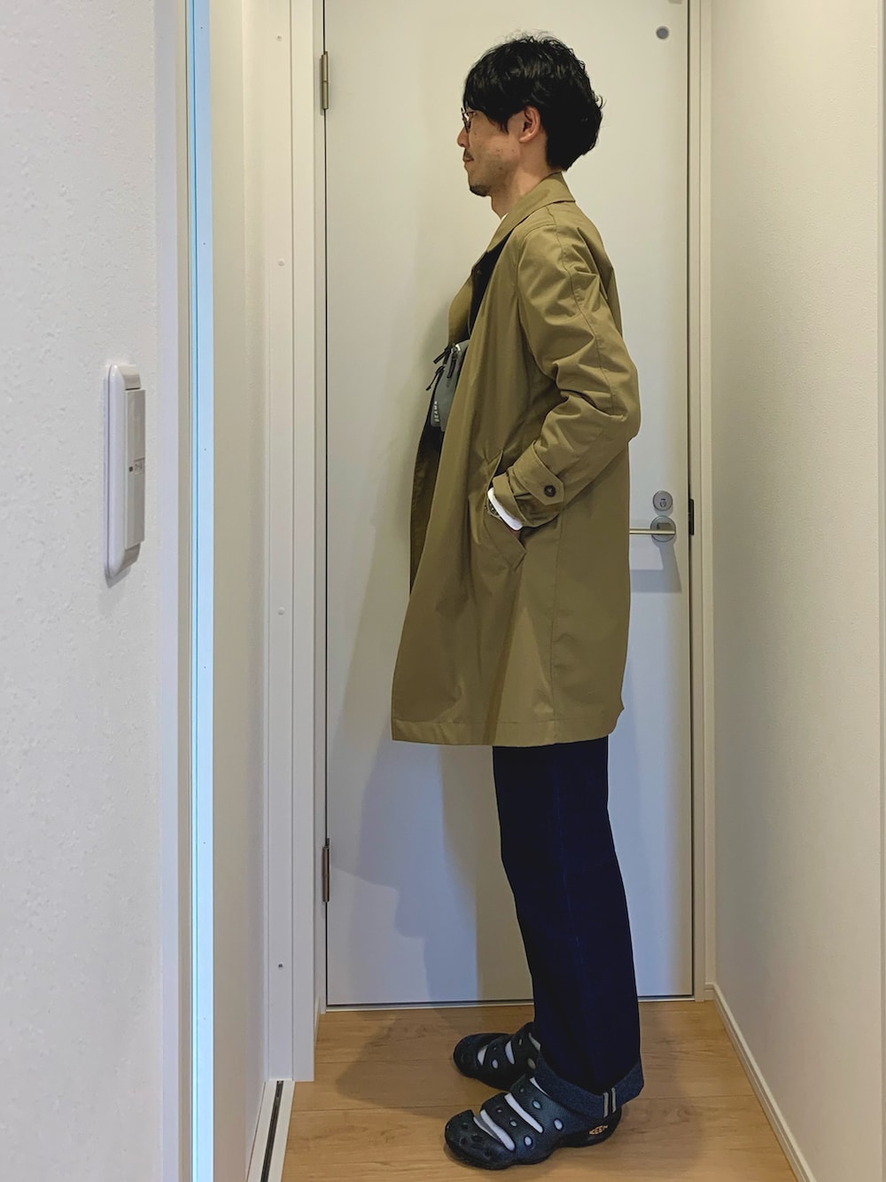 ベージュ系のステンカラーコート、ホワイト系のシャツ/ブラウス、グレー系のショルダーバッグを着用したメンズの春コーディネートの2枚目の写真