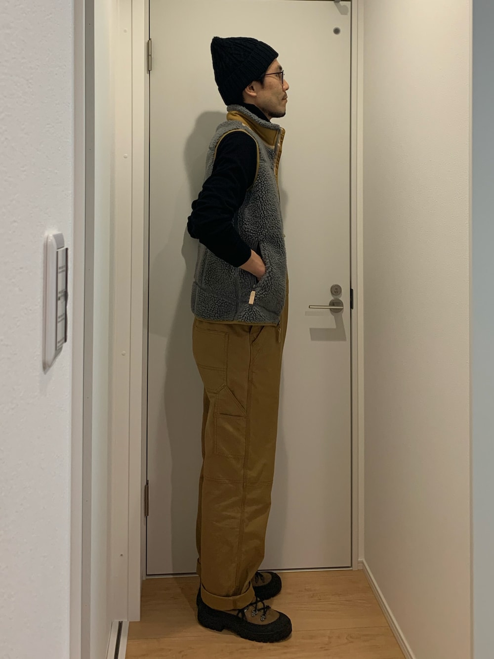 ブラウン系のサロペット/オーバーオール、グレー系のベスト、ブラウン系のブーツを着用したメンズの冬コーディネートの2枚目の写真