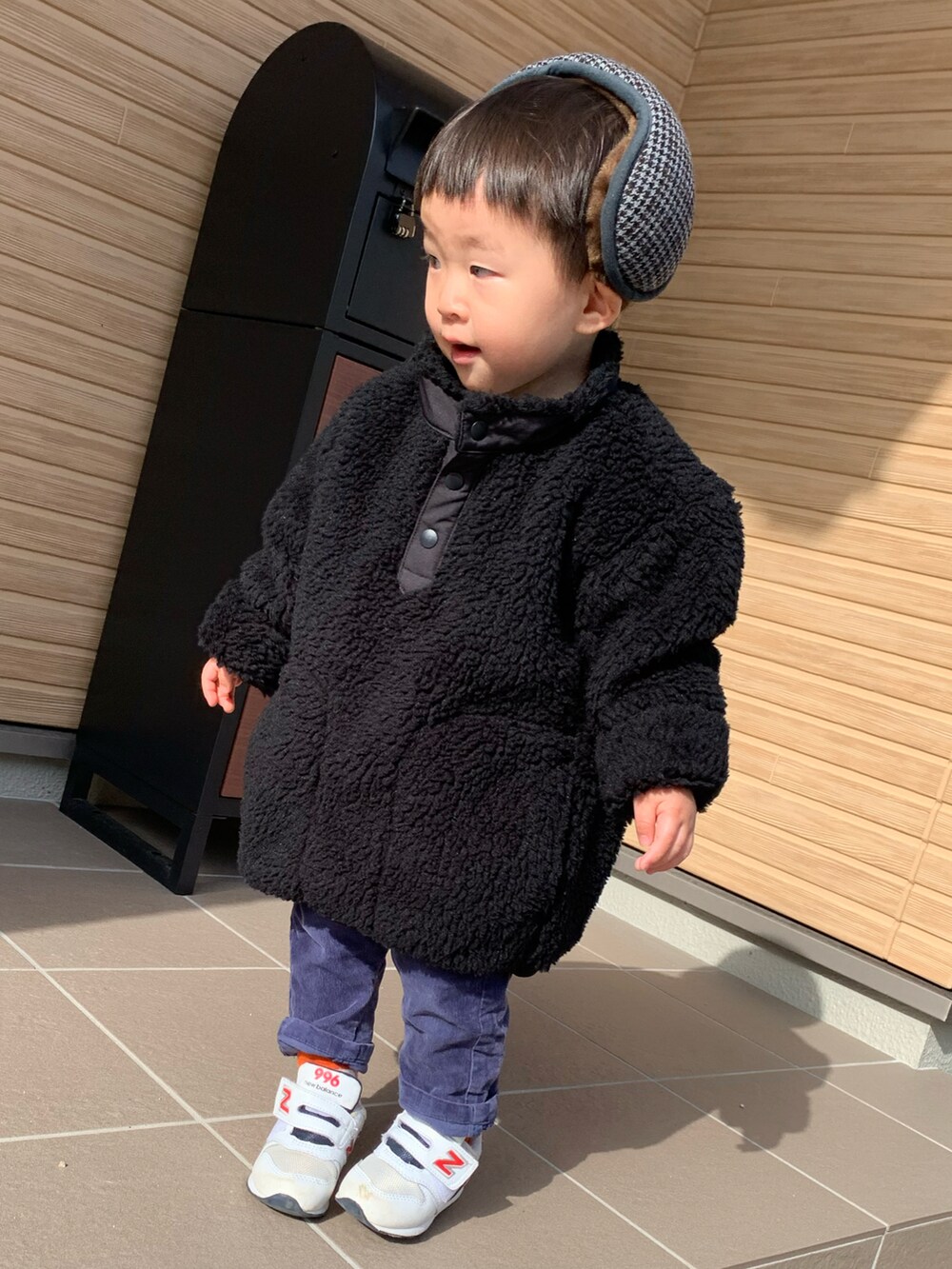 ブラック系のトップス、ホワイト系のスニーカー、グレー系のイヤーマフを着用したメンズの冬コーディネートの3枚目の写真